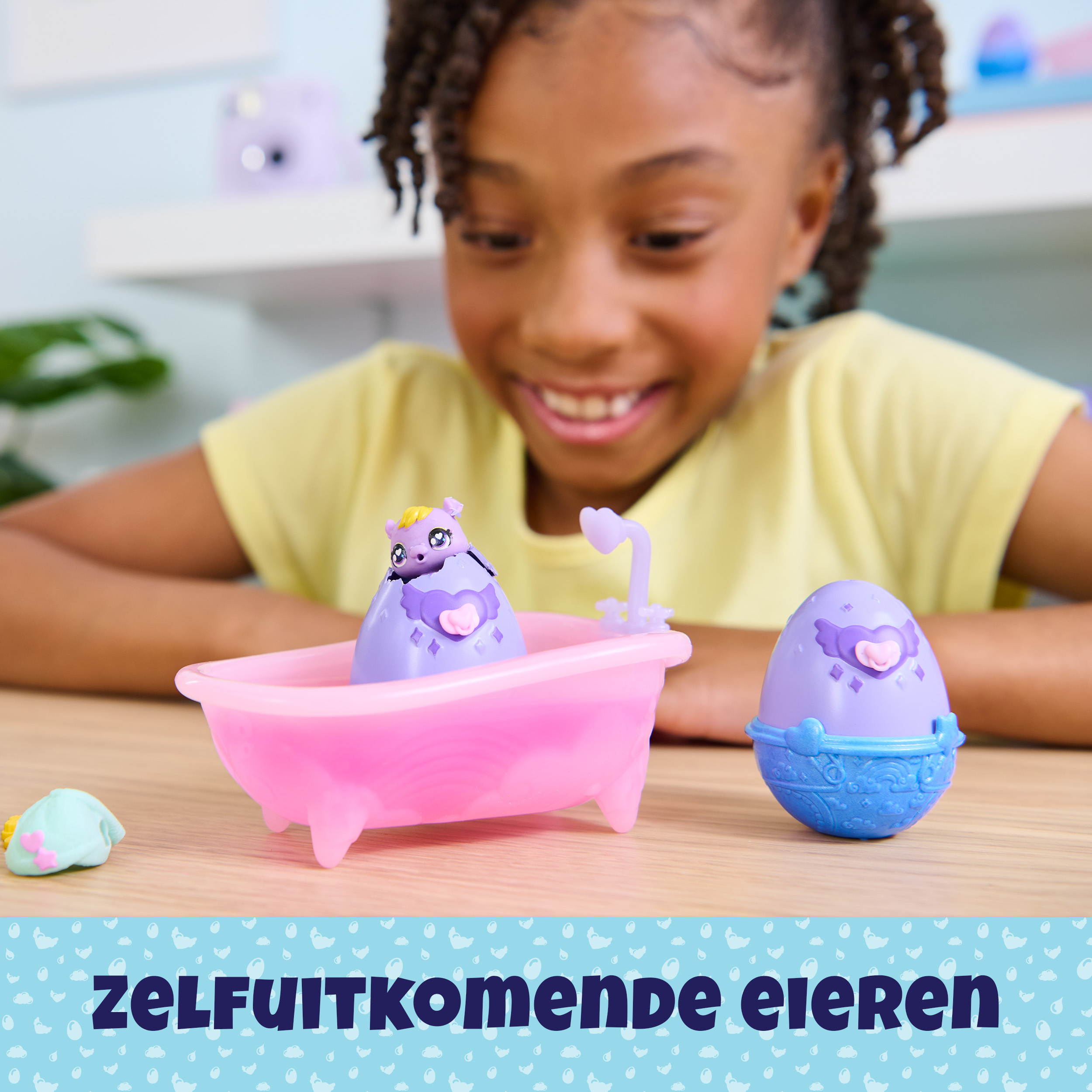 Ein Mädchen lächelt auf eine Spielzeugbadewanne mit einem lila Wesen und Ei. Blaues Wasser-Design unten.