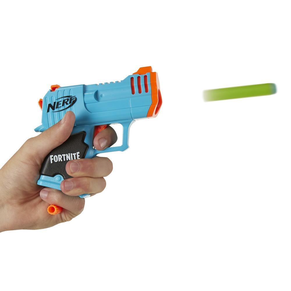 Eine Hand hält eine blaue und orangefarbene Nerf Fortnite-Pistole, die einen grünen Pfeil auf weißem Hintergrund abfeuert.