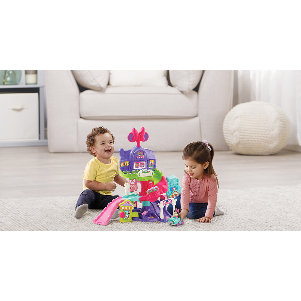Zwei Kinder spielen mit einem Minnie Mouse Spielset auf einem Teppich.