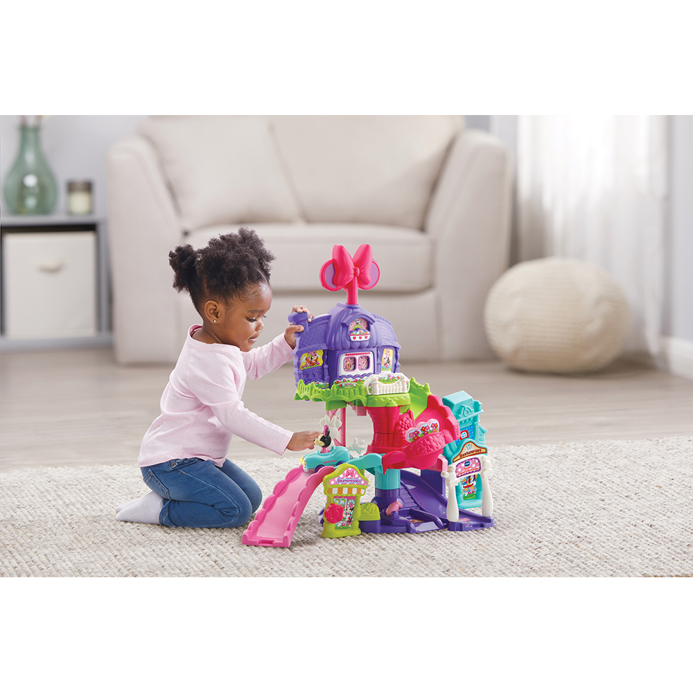 Ein Mädchen spielt mit einem Minnie Mouse Spielset auf einem Teppich.