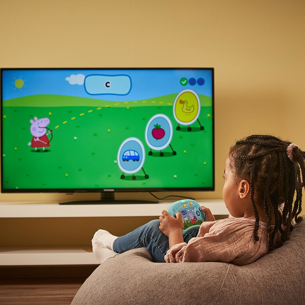 Ein Mädchen spielt mit einem Controller ein Spiel auf einem Fernseher.