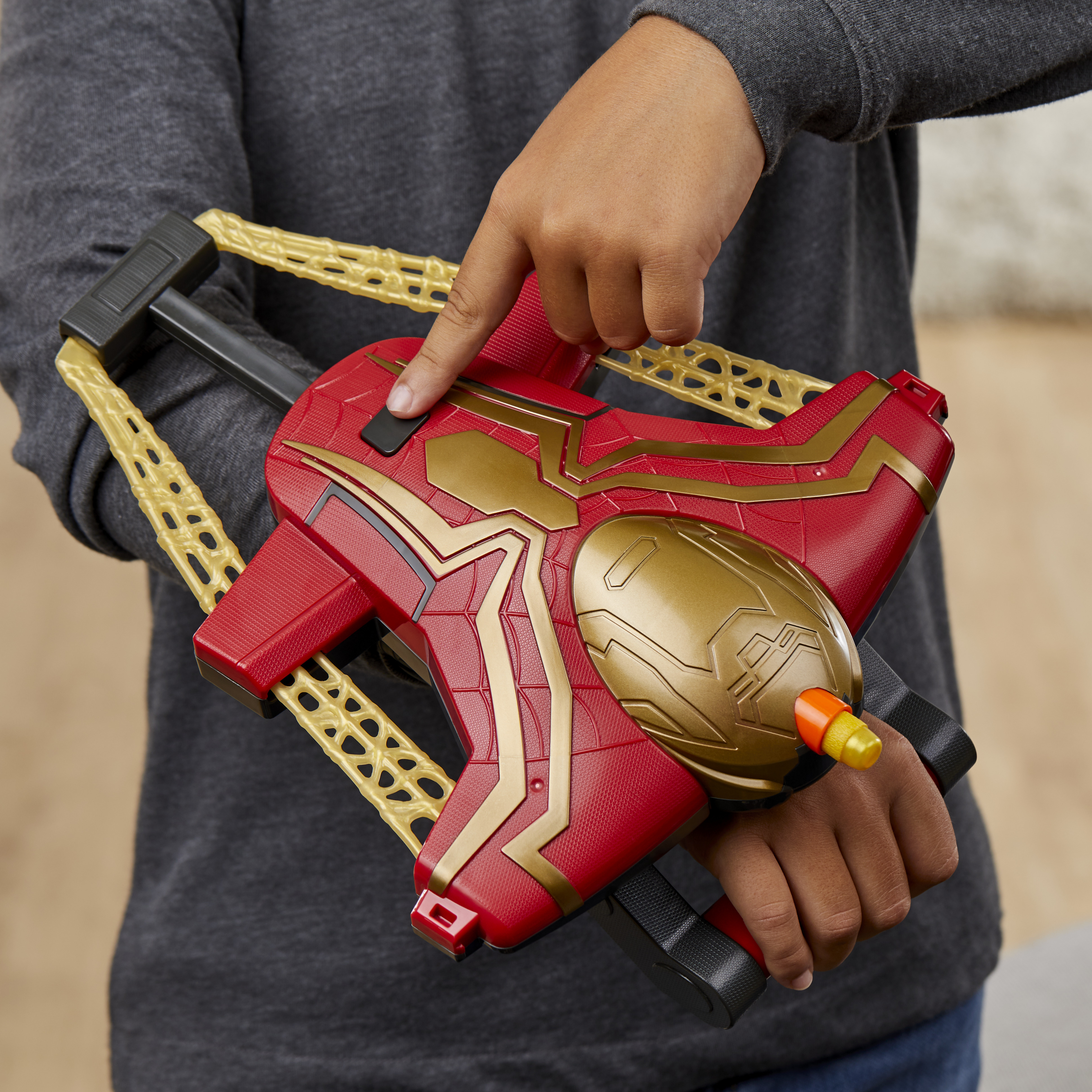 Ręce dziecka trzymające czerwoną i złotą zabawkę z żółtymi miotaczami sieci.