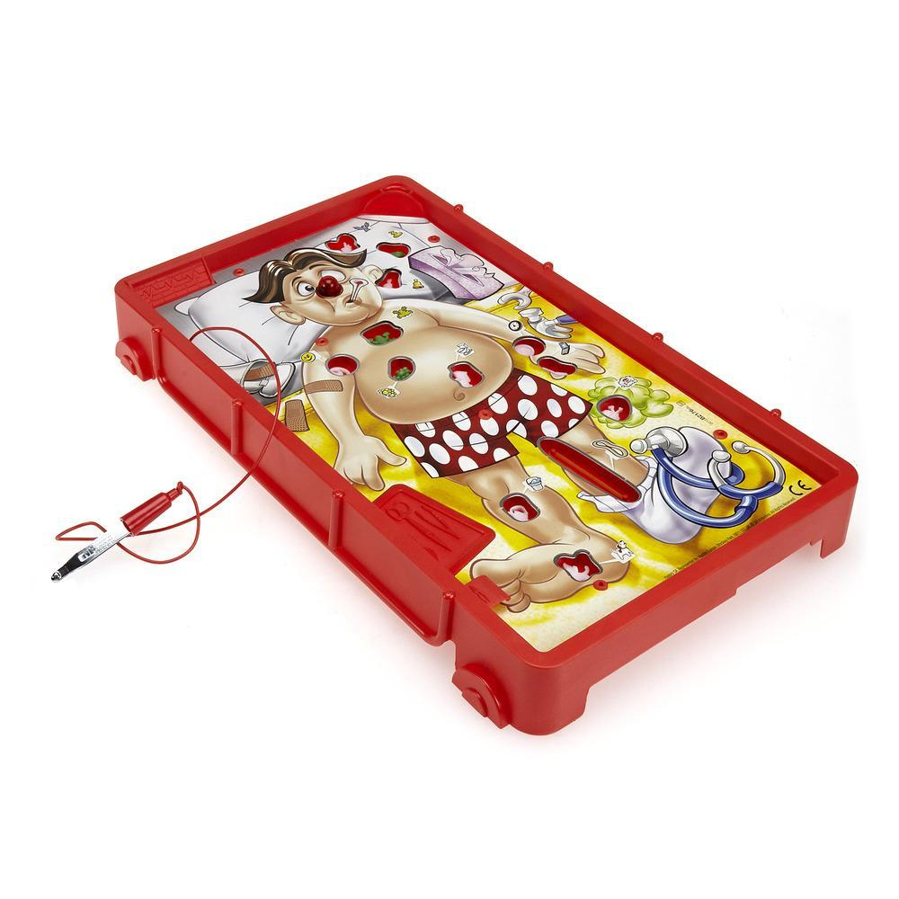 Zabawka przedstawia osobę na łóżku z czerwonym ciałem i narządami wewnętrznymi. Obecne są narzędzia chirurgiczne.