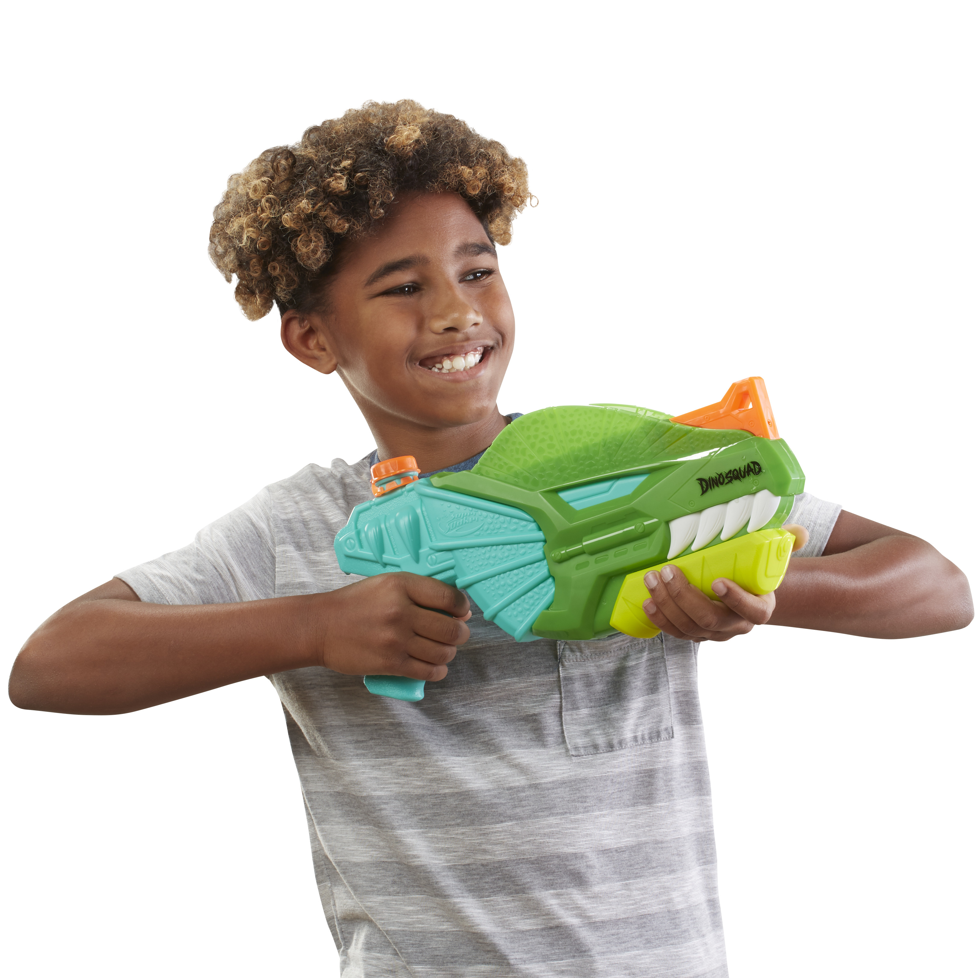 Un ragazzino sorride mentre tiene in mano una pistola ad acqua a forma di dinosauro verde e arancione.