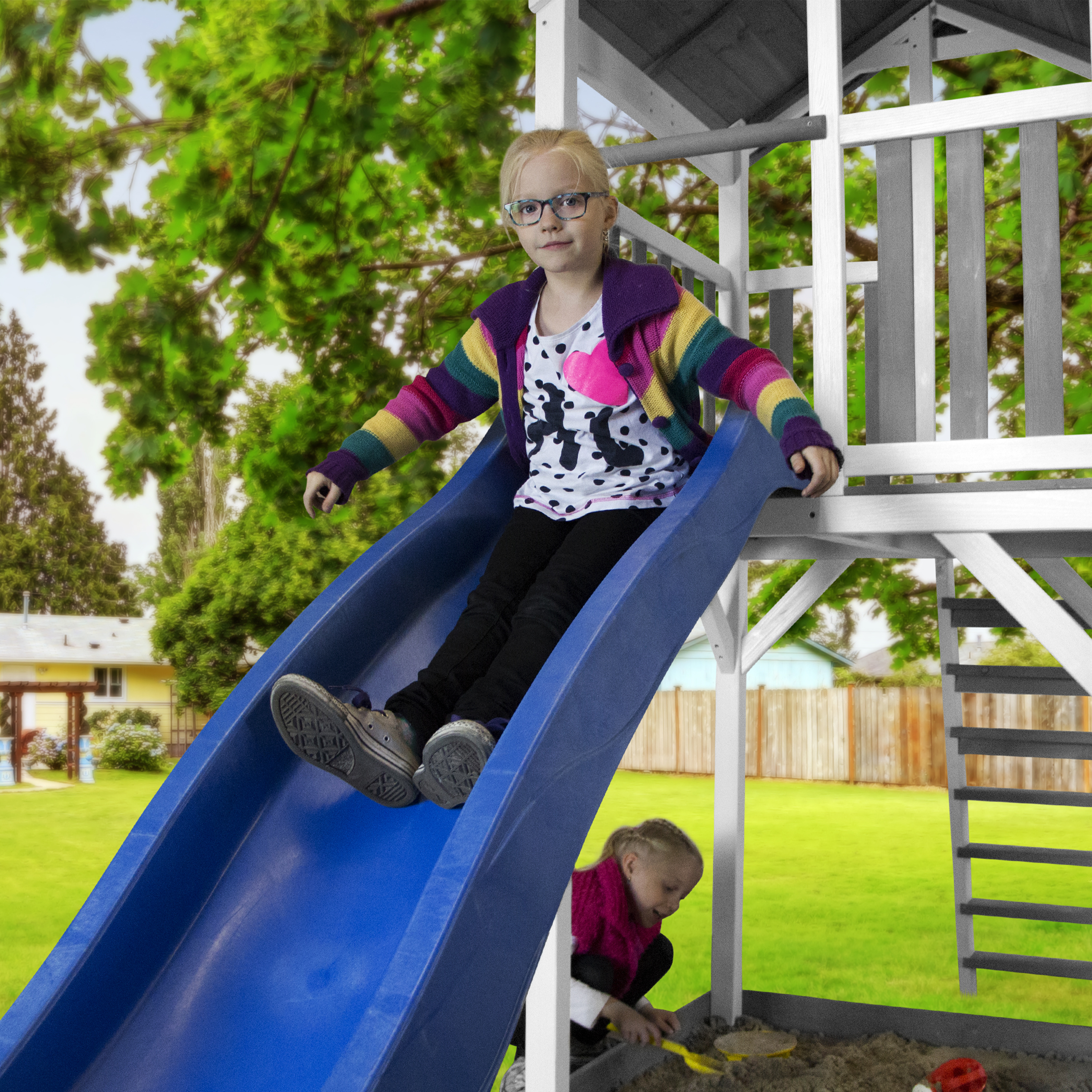 Zwei Kinder spielen auf einer Spielplatzrutsche, eines rutscht runter, eines unten.
