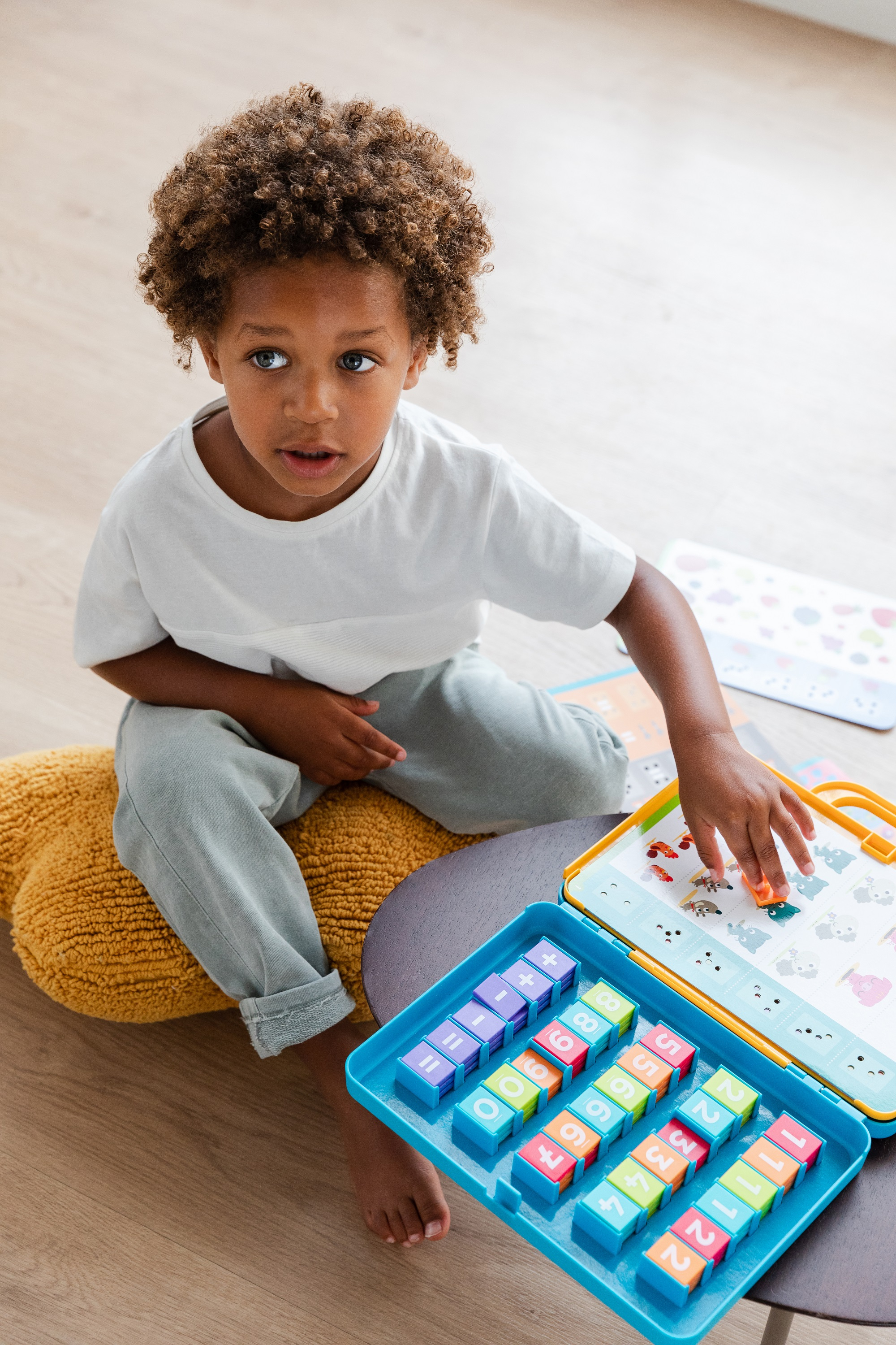 Ein kleiner Junge sitzt und spielt mit bunten Blöcken auf einer blauen Ablage.