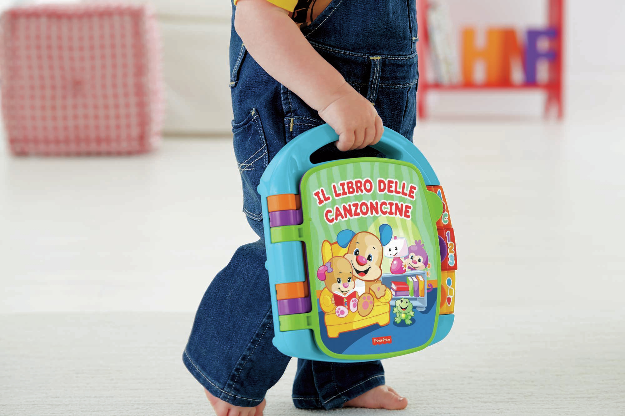 Dziecko trzymające kolorową książkę zatytułowaną 'Il libro delle canzoncine' z ilustracjami postaci z kreskówek.