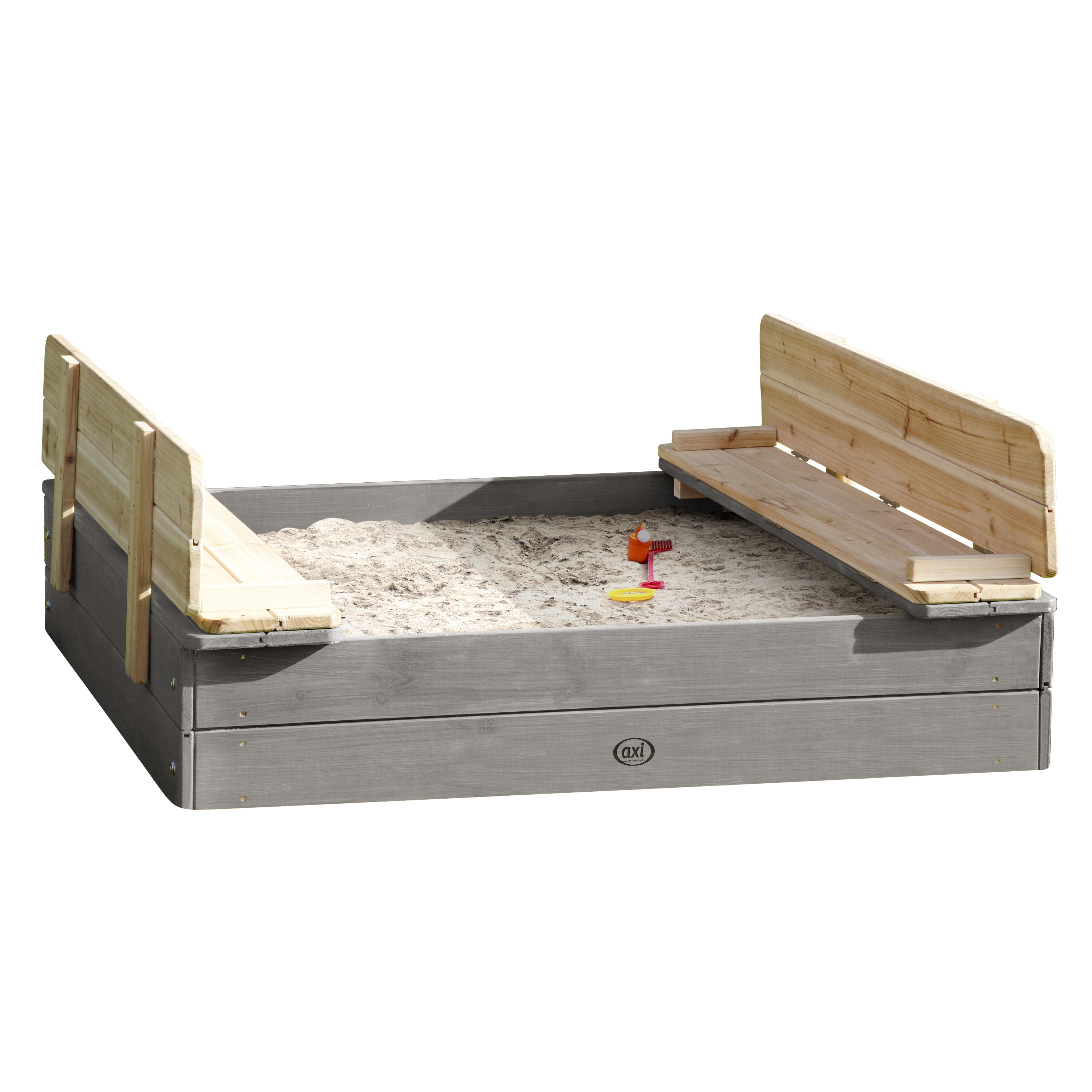 Ein Sandkasten mit Holzrahmen und Bänken. Sand und Spielzeug sind drin, spielbereit. Es ist grau.