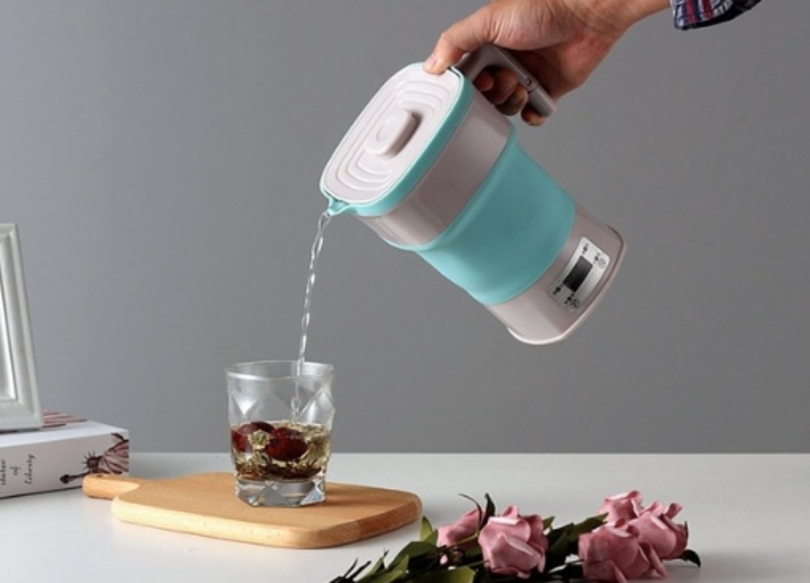 Eine Person gießt Wasser aus einem faltbaren elektrischen Wasserkocher in ein Glas mit Essen.