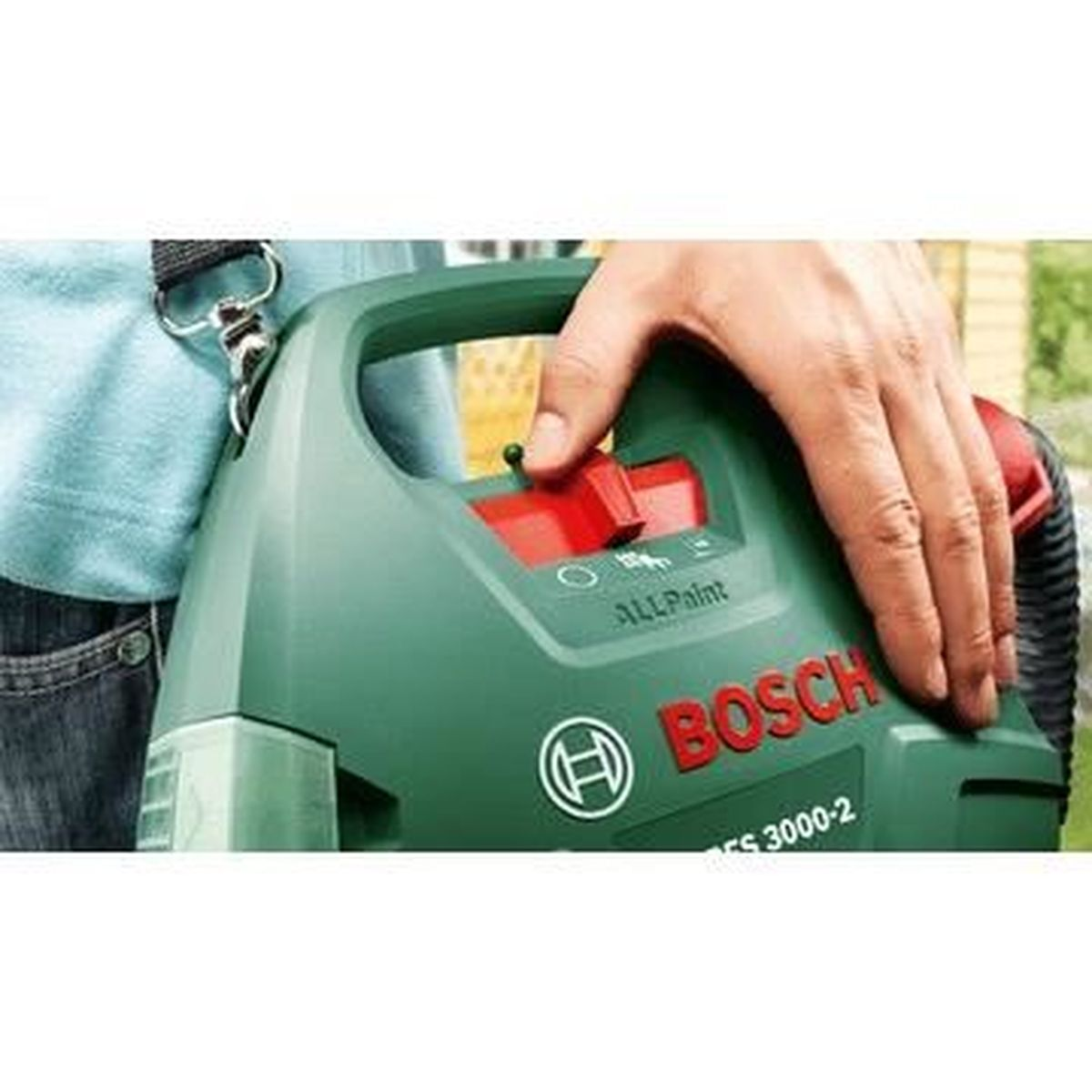 Una mano preme un pulsante rosso su uno spruzzatore di vernice Bosch verde con manico nero.