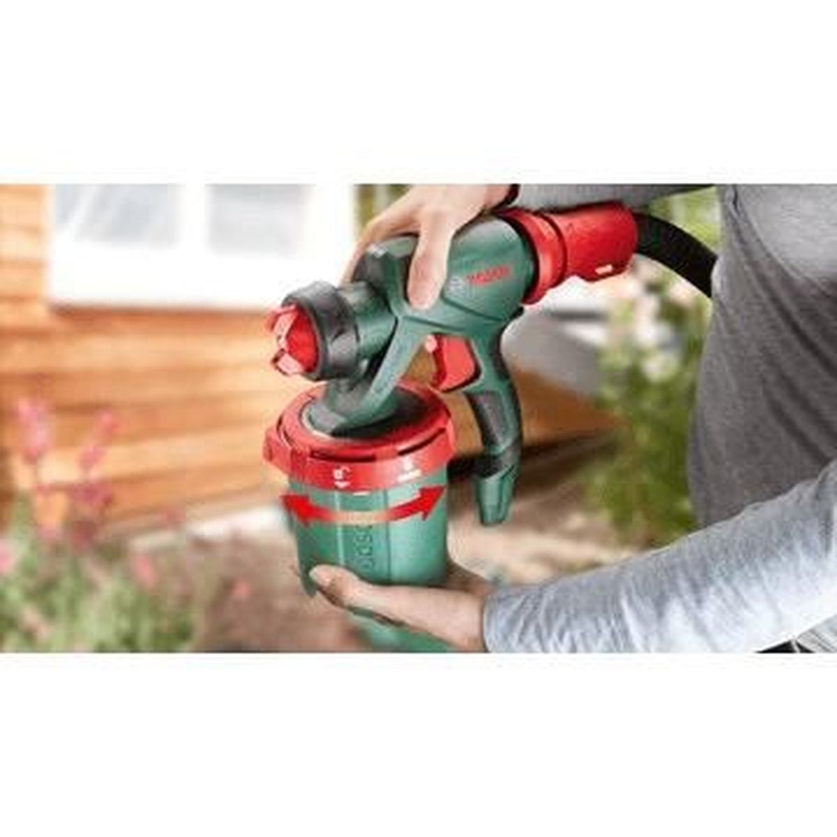 Una persona che tiene uno spruzzatore di vernice Bosch verde e rosso con ugello rosso.