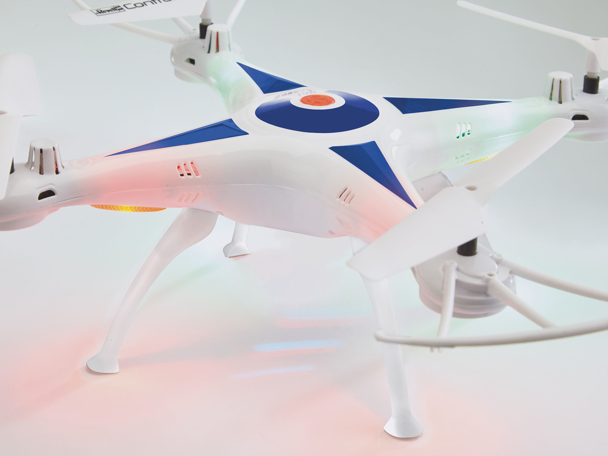 Biały dron z niebieskimi akcentami i światłami. Dron ma cztery śmigła i znajduje się na białym tle.