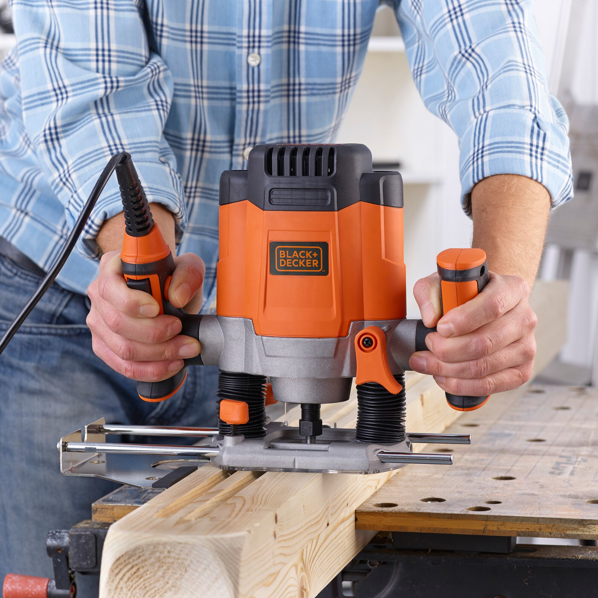 Persona usando fresadora Black+Decker para cortar tabla de madera en banco.
