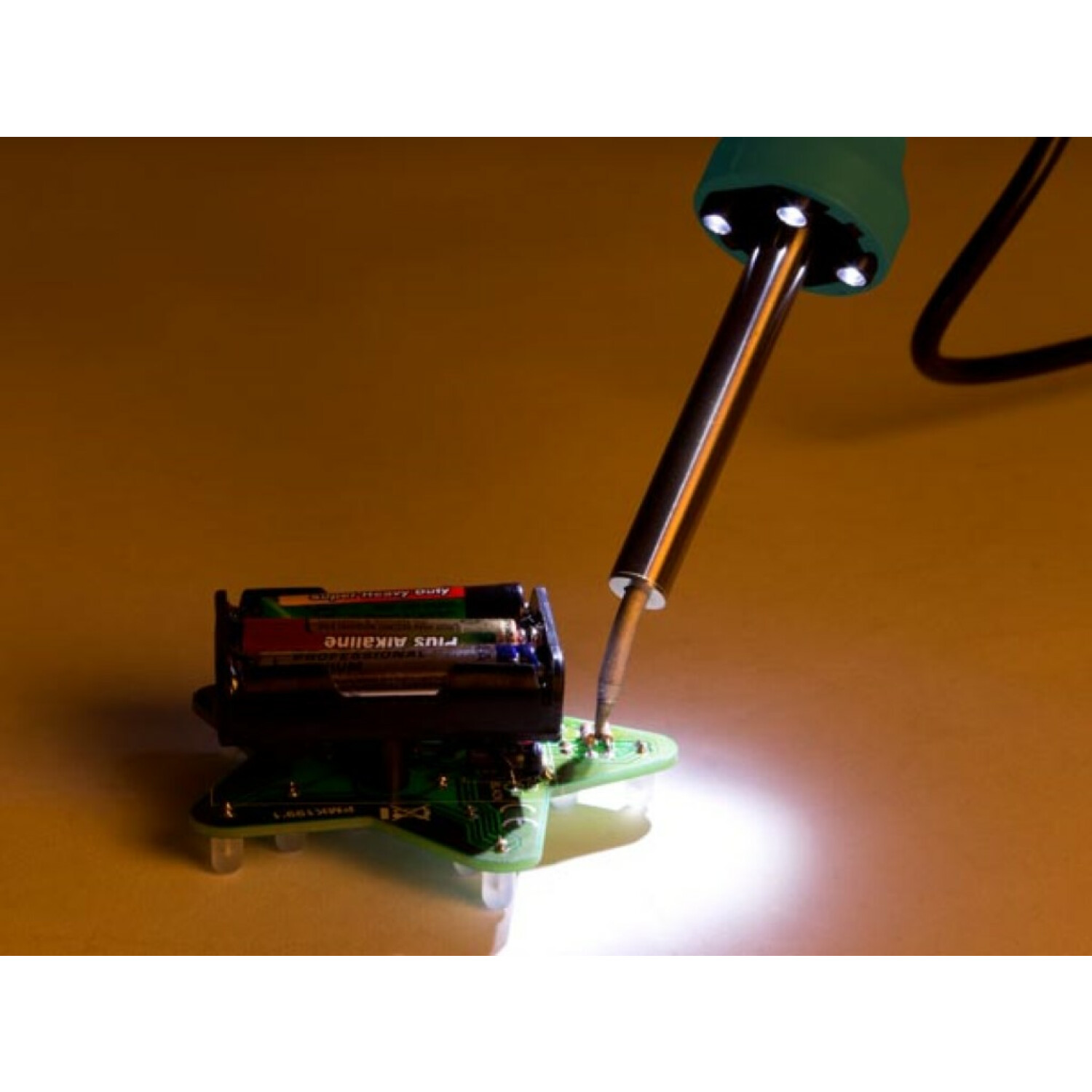 Saldatore su un circuito stampato con batterie. La punta è calda e incandescente.
