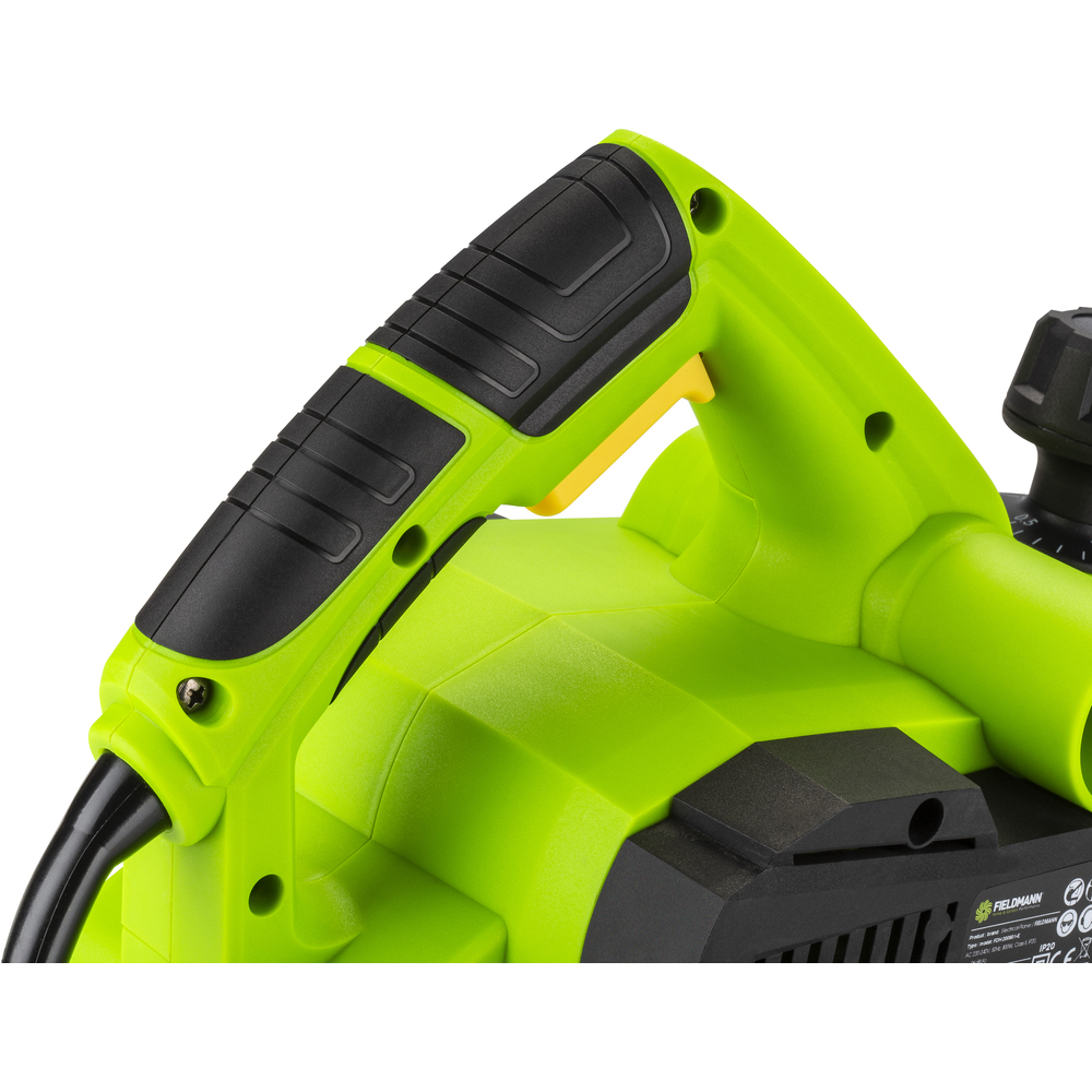 Zbliżenie uchwytu zielonej elektrycznej strugarki ręcznej z czarnymi detalami i żółtym przyciskiem. Białe tło.