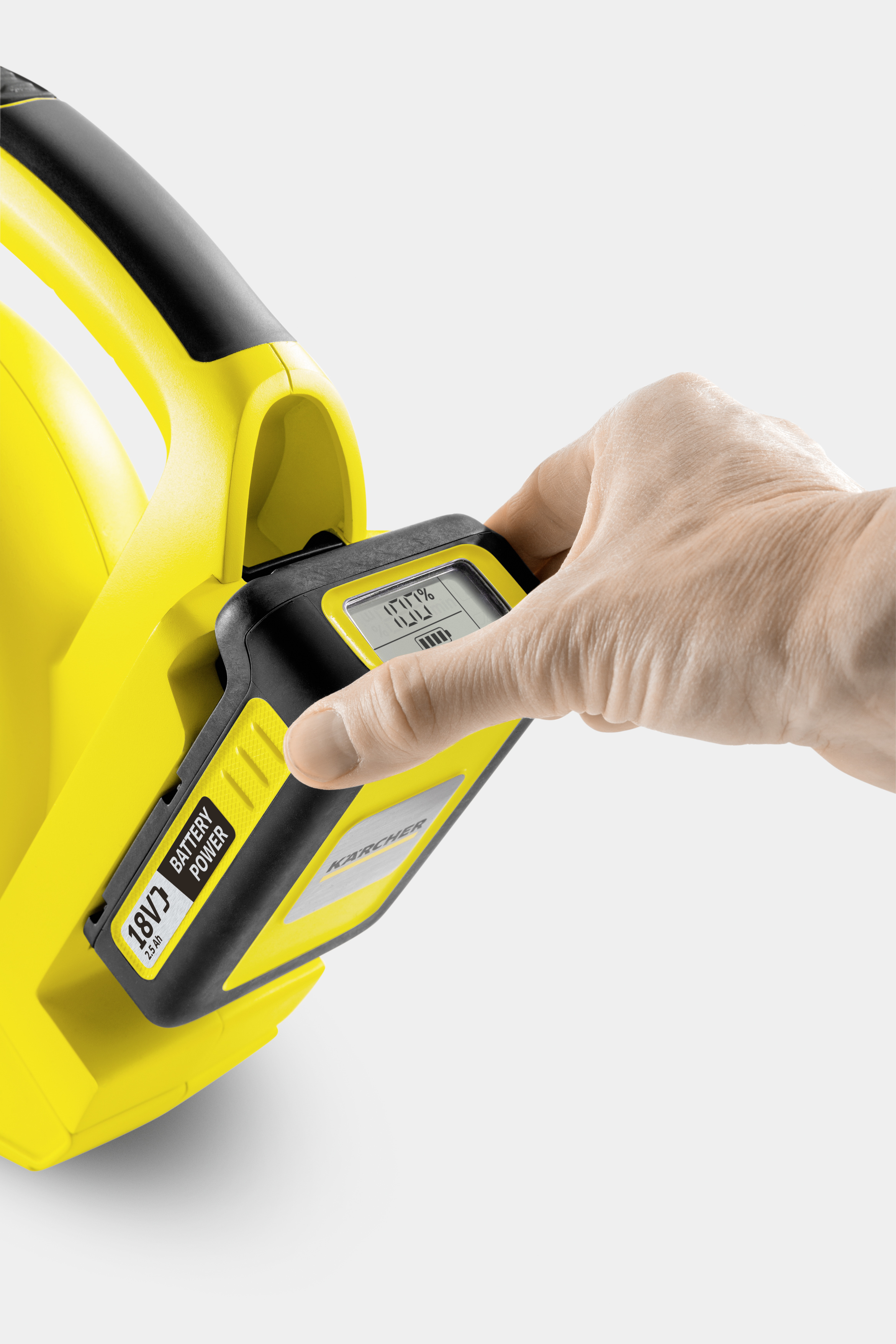 Ręka wkładająca baterię do żółto-czarnego elektronarzędzia.