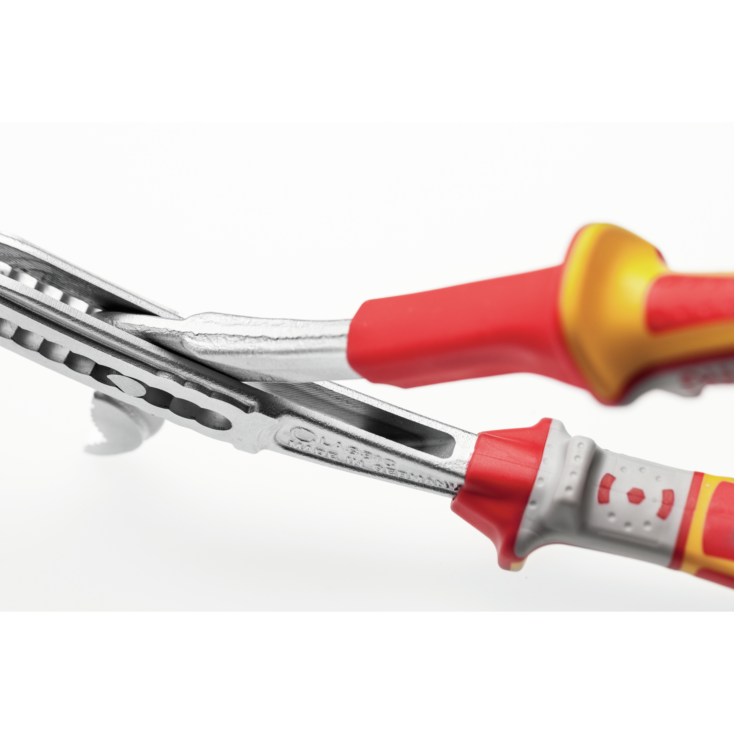 Szczypce, srebrny korpus, czerwono/żółte uchwyty. Białe tło. Zbliżenie.