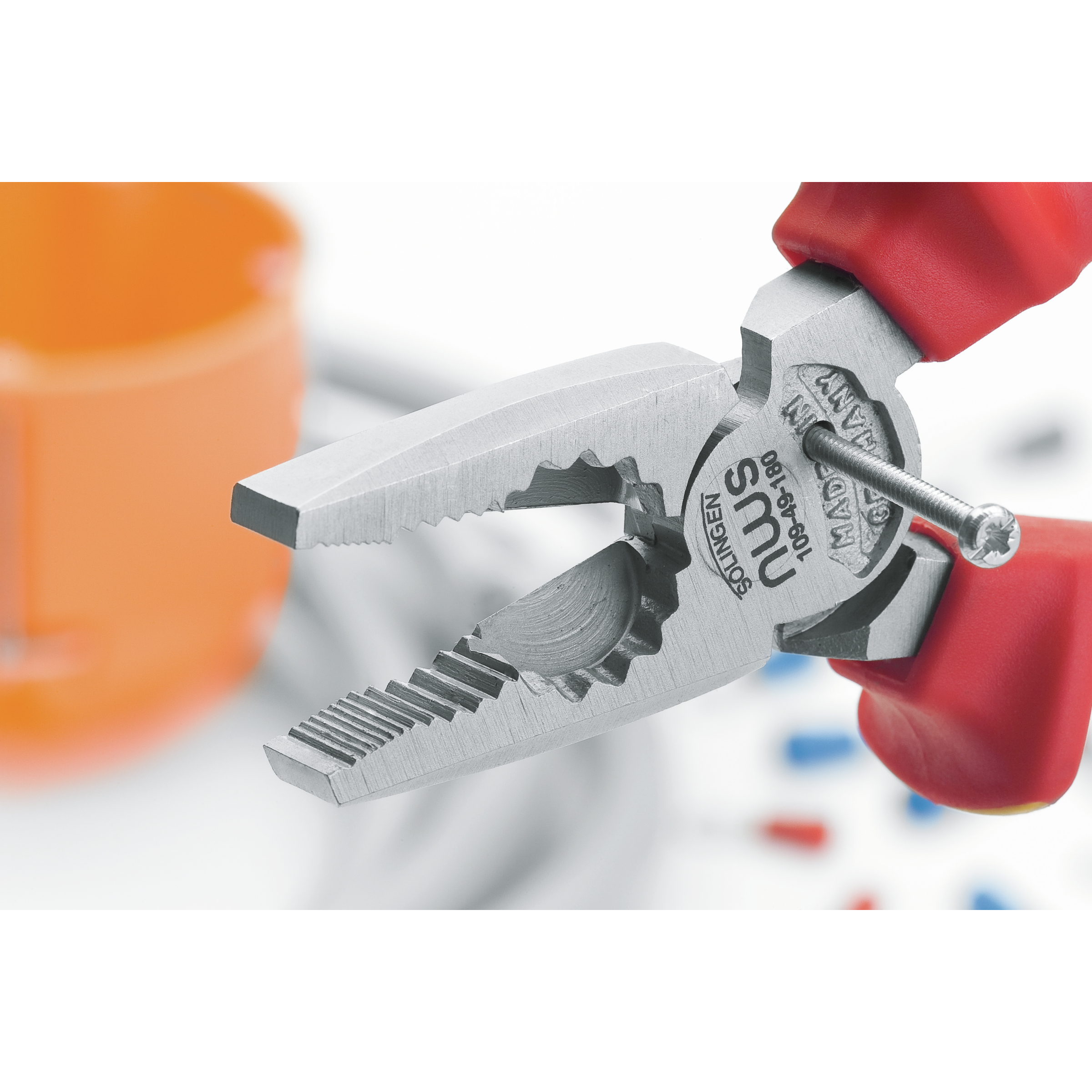 Szczypce trzymające śrubę. Czerwono-żółte uchwyty, srebrne szczęki. Białe tło.