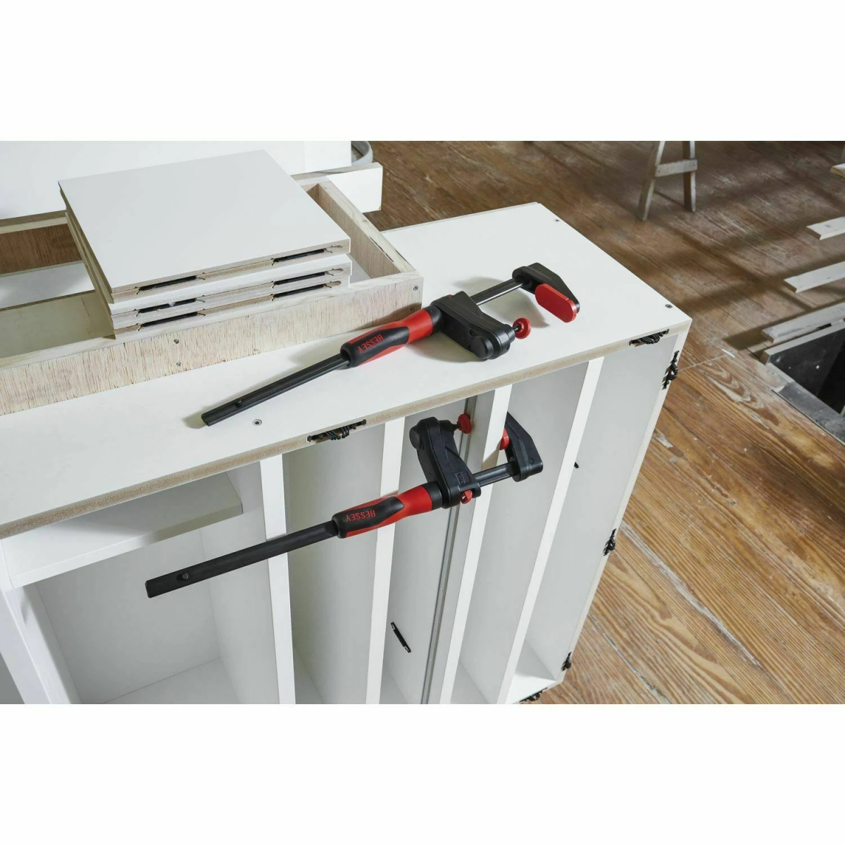 Due morsetti su un armadietto bianco, con assi di legno sullo sfondo.
