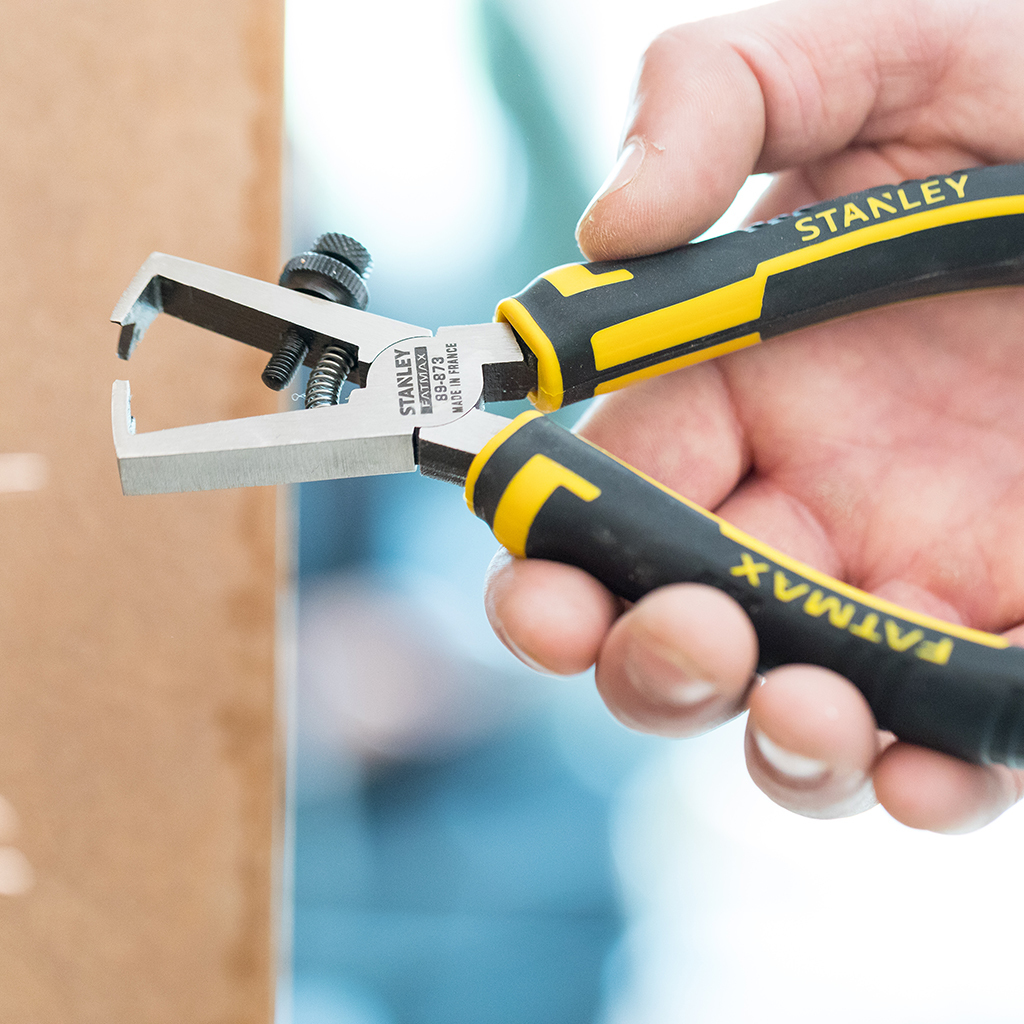 Hand hält einen Stanley FatMax Drahtabisolierer. Gelbes und schwarzes Werkzeug, FatMax und Stanley.