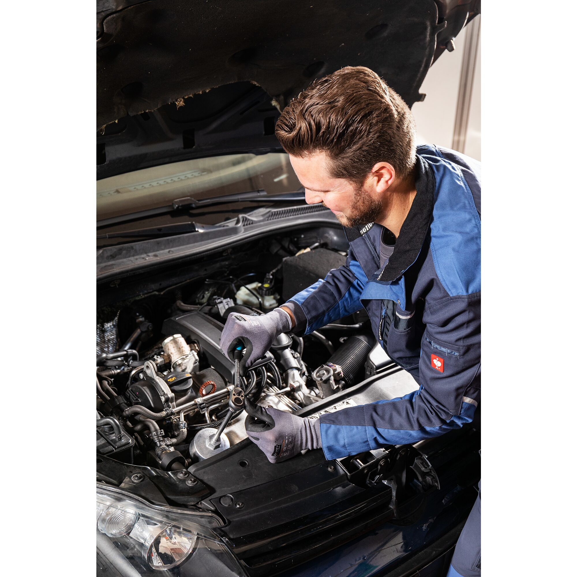 Mecánico trabajando en un motor de coche con herramientas, en un taller.