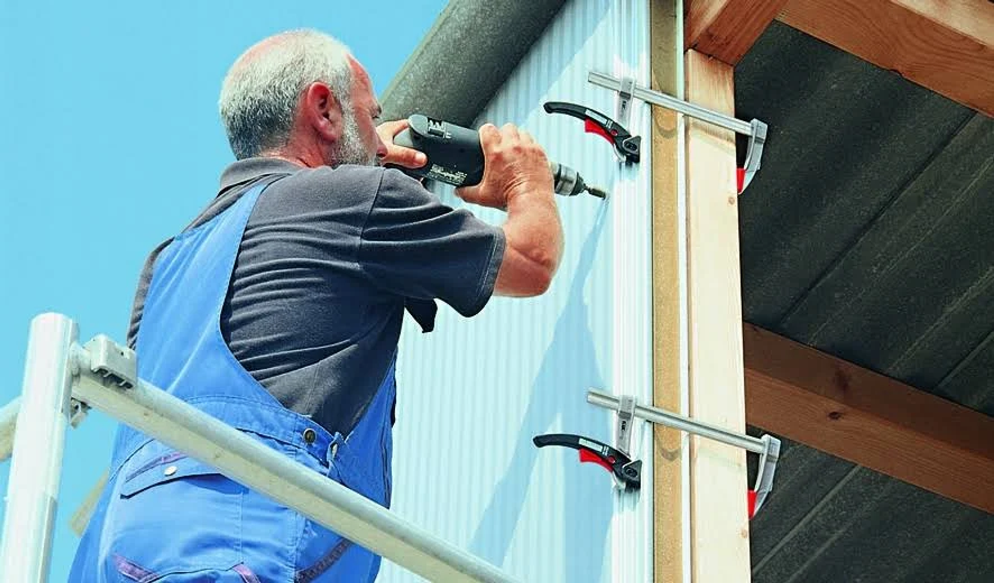 Un hombre usa un taladro para fijar tornillos. Utiliza abrazaderas para sujetar la madera en su lugar.