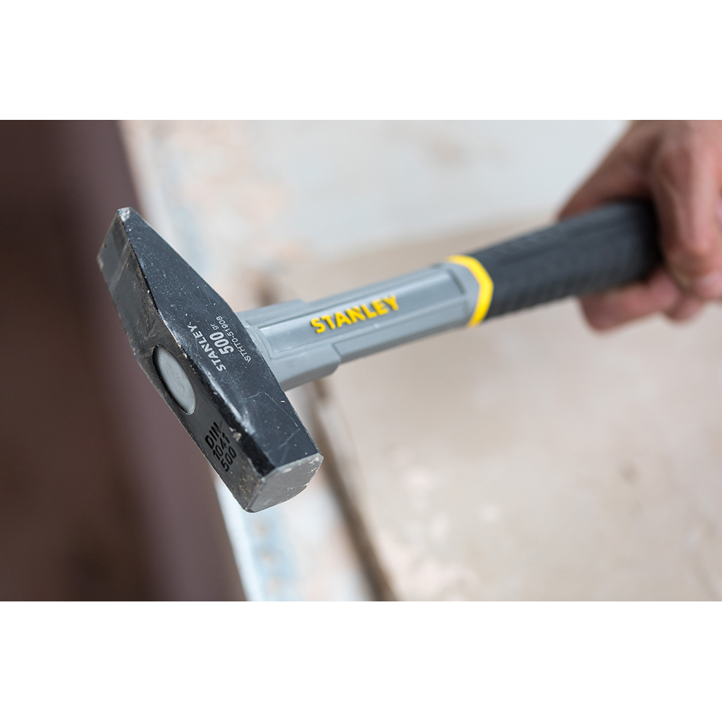 Zbliżenie czarno-szarego młotka z żółtym akcentem, który jest trzymany.