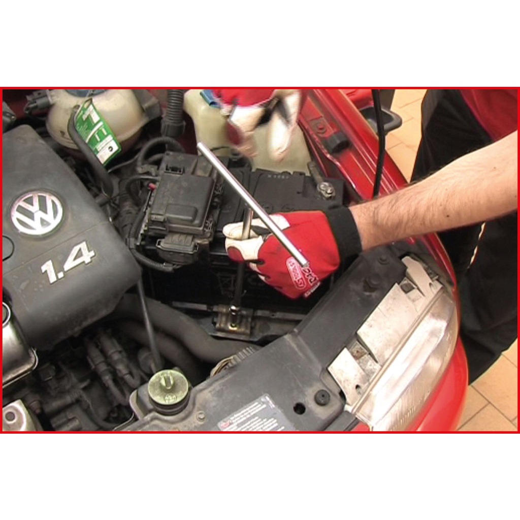 Eine Person benutzt ein T-förmiges Werkzeug in einem Automotor.