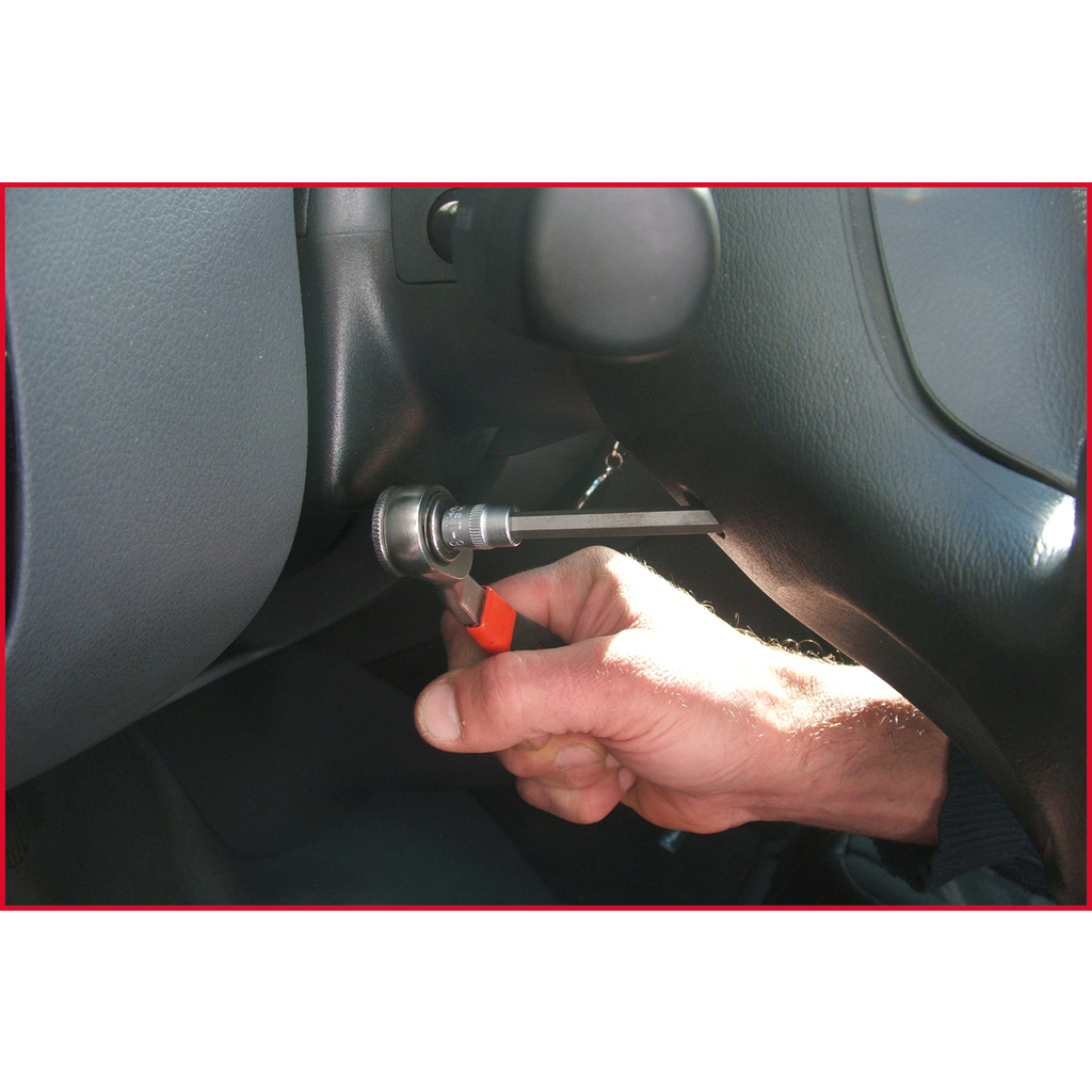 Eine Hand hält eine Ratsche mit einem Schraubendreher-Bit und arbeitet am Armaturenbrett eines Autos.