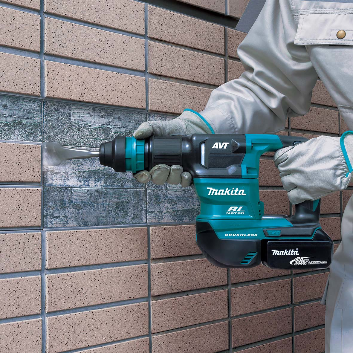 Una persona usando un taladro percutor Makita, para romper una pared de ladrillos.