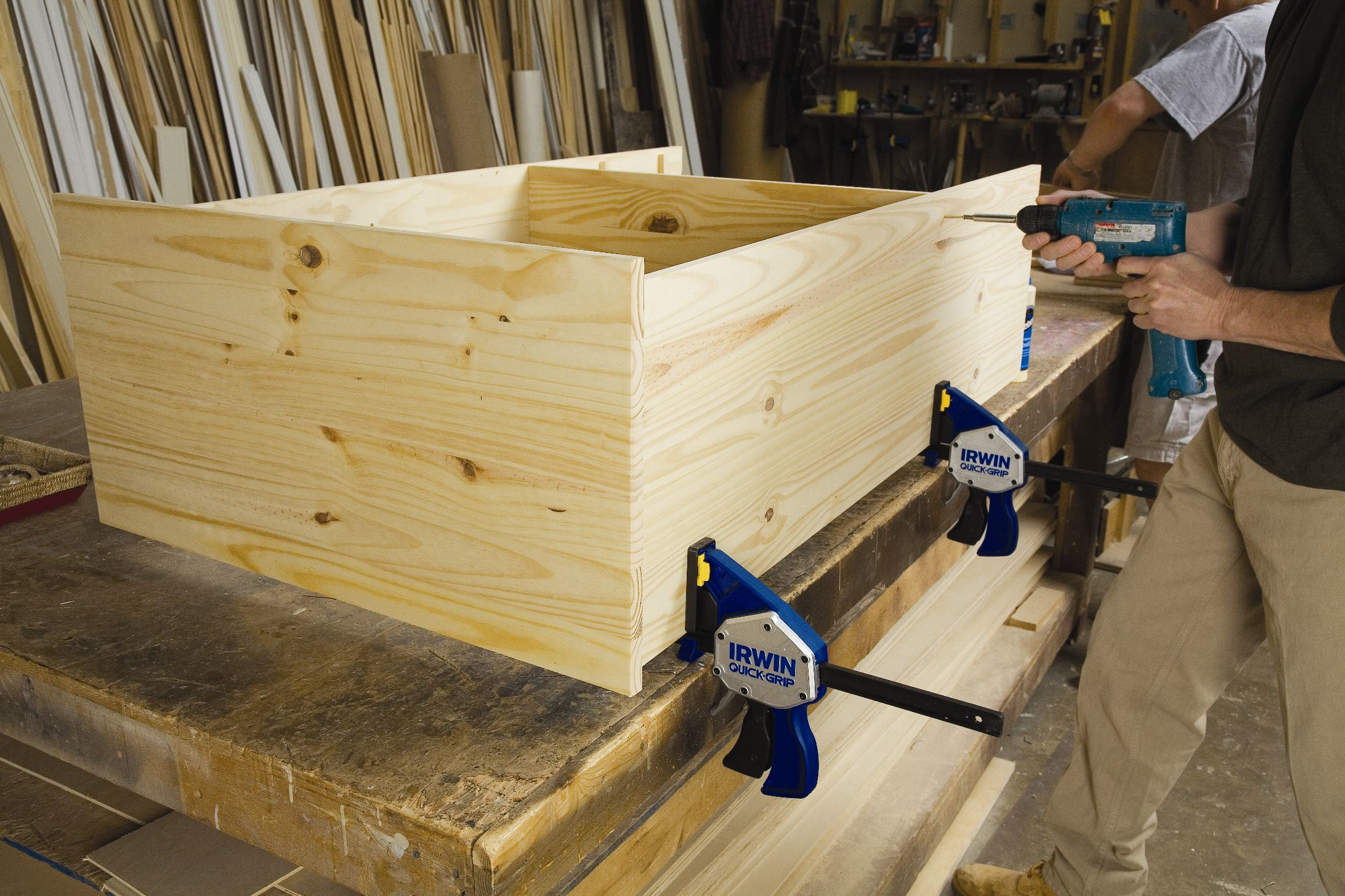 Ein Arbeiter verwendet Irwin Quick-Grip Klemmen auf einer Holzkiste.