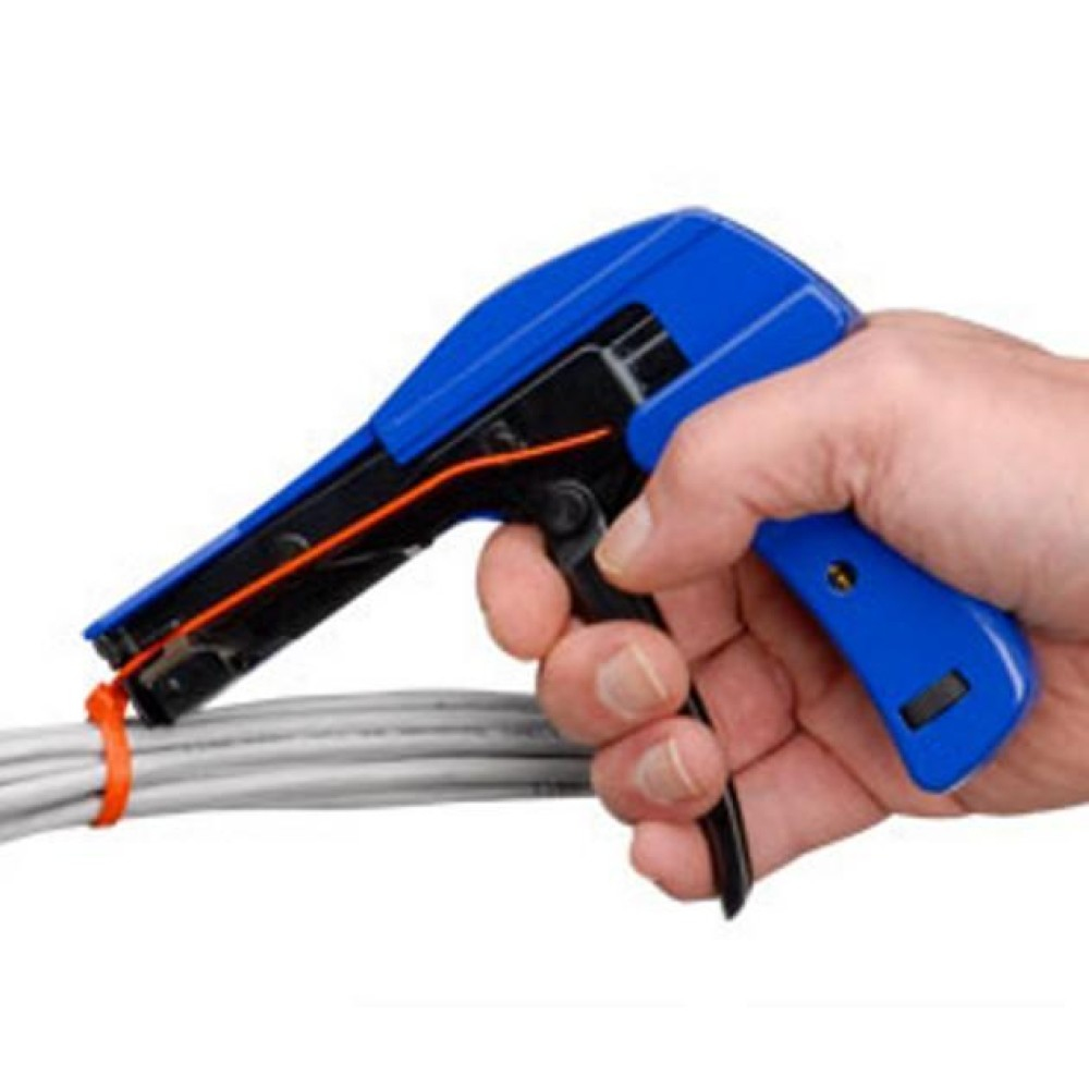 Mano de una persona usando una pistola azul para bridas para sujetar un haz de cables. Interior.