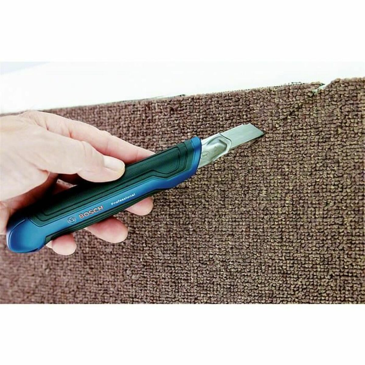 Hand schneidet mit blauem Messer braunen Teppich.