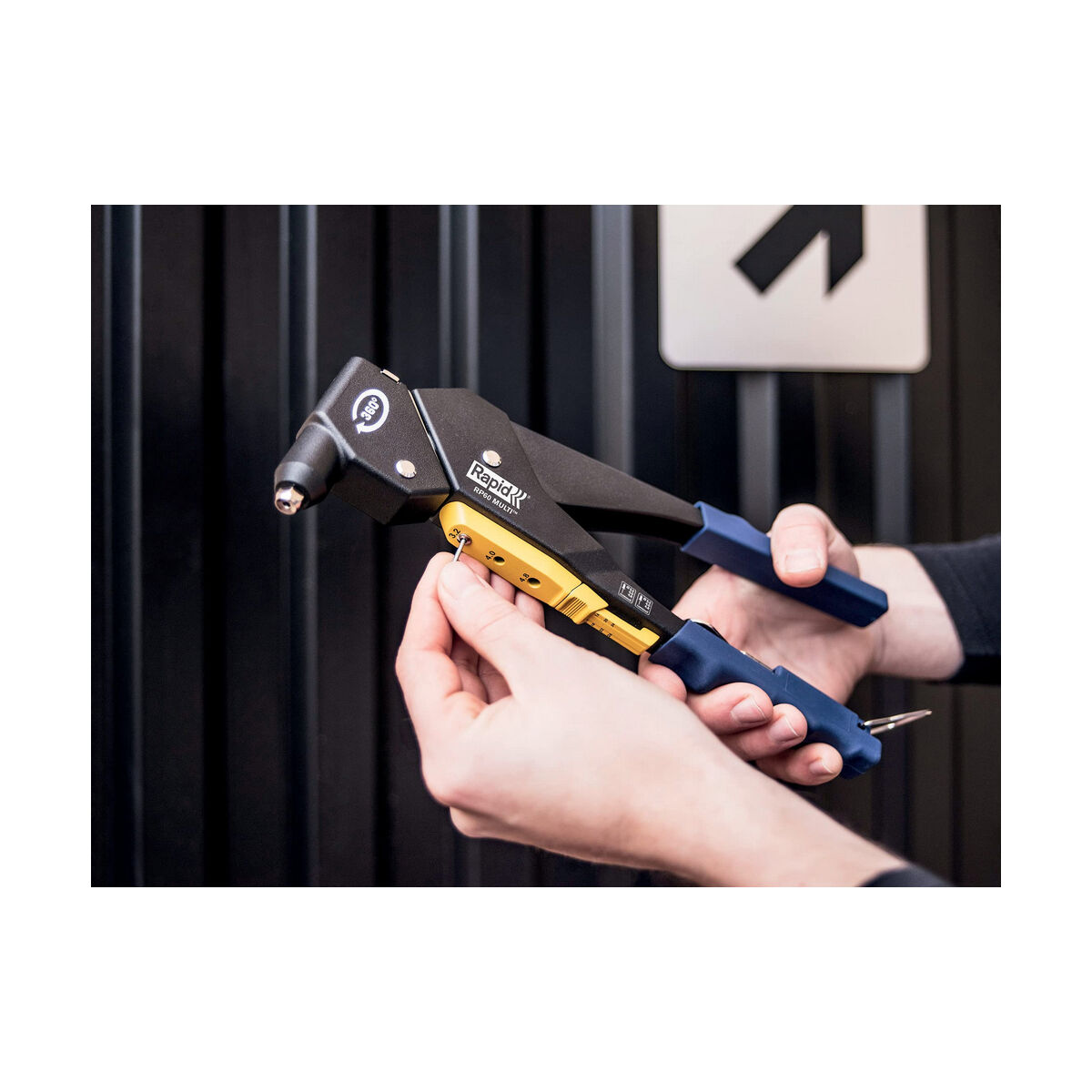Hände, die ein Rapid RP80 Multi-Nietgerät benutzen. Schwarz-blaues Nietgerät, Person hält Werkzeug.