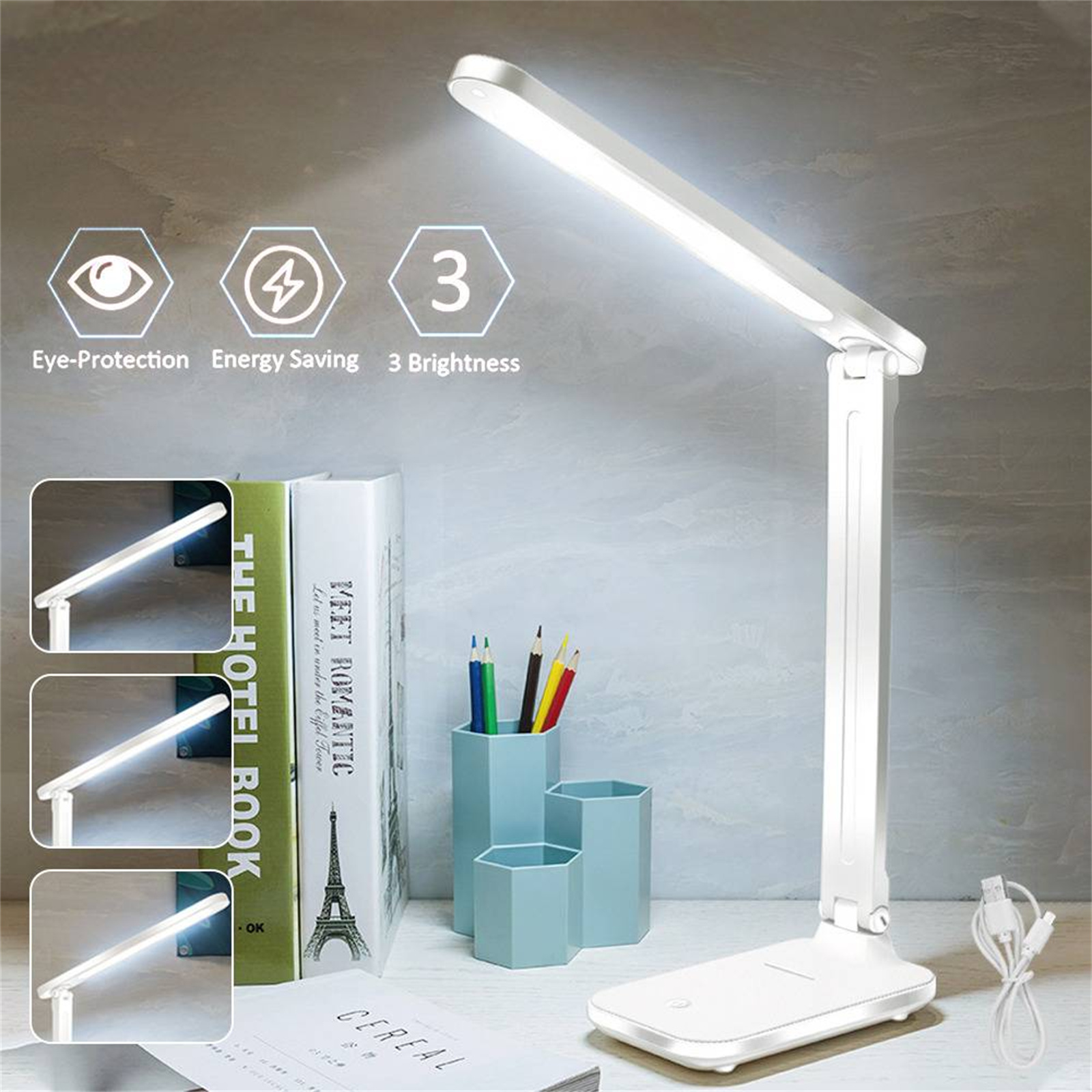 Eine weiße Schreibtischlampe, die Licht mit drei Helligkeitseinstellungen ausstrahlt, mit Büchern, Stiften und Dekorationen.