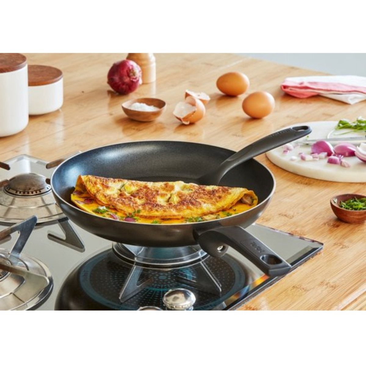 Omelette dans une poêle sur une cuisinière avec des ingrédients à proximité.
