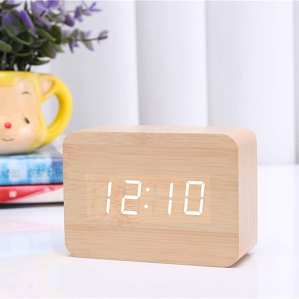 Digitaluhr aus Holz, die 12:10 anzeigt. Andere Objekte befinden sich im Hintergrund.