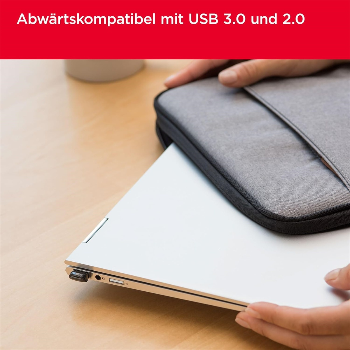 Ein Laptop und ein USB-Gerät. Hände stecken den USB-Stick in den Laptop.