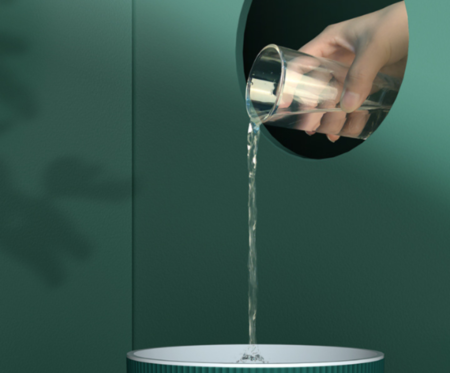 Eine Hand gießt Wasser aus einem Glas in eine Schüssel, mit abstraktem grünem Hintergrund.