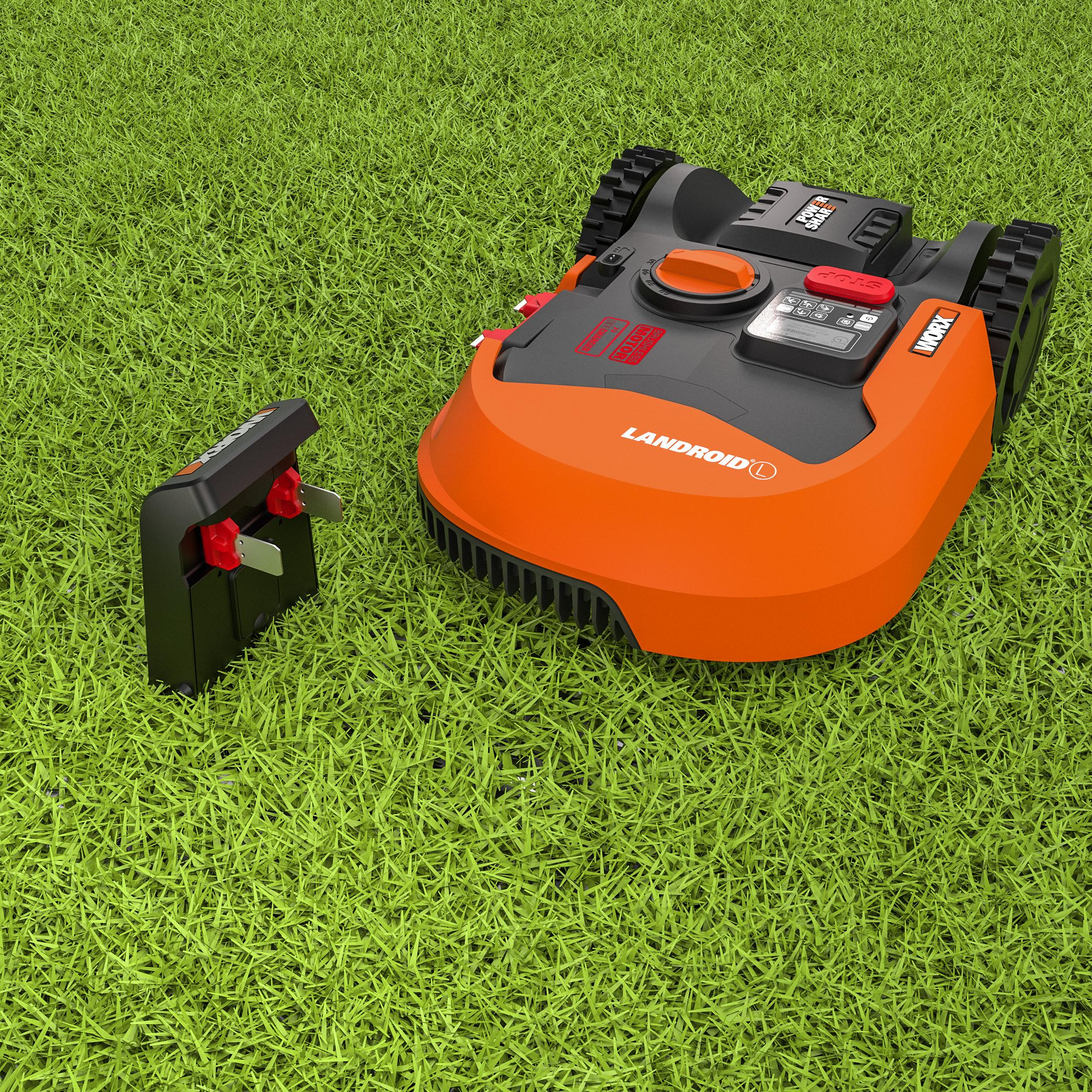 Robot-Rasenmäher auf Gras. Oranger Mäher und Ladestation sind sichtbar.