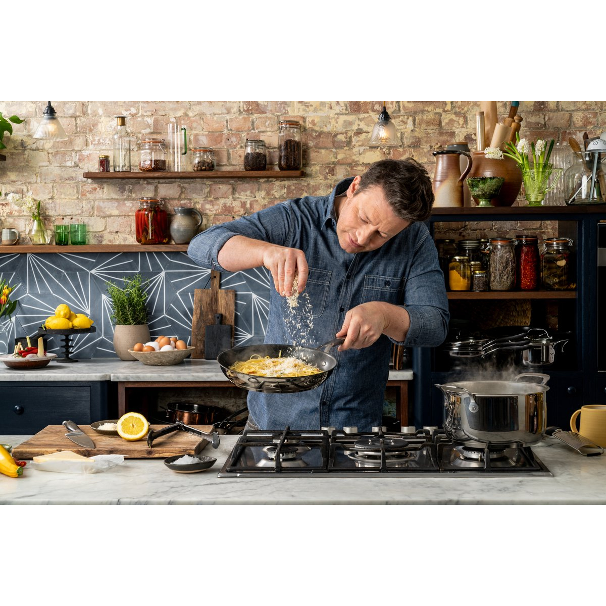 Man die in een keuken kookt en kruiden toevoegt aan voedsel in een pan op een fornuis.