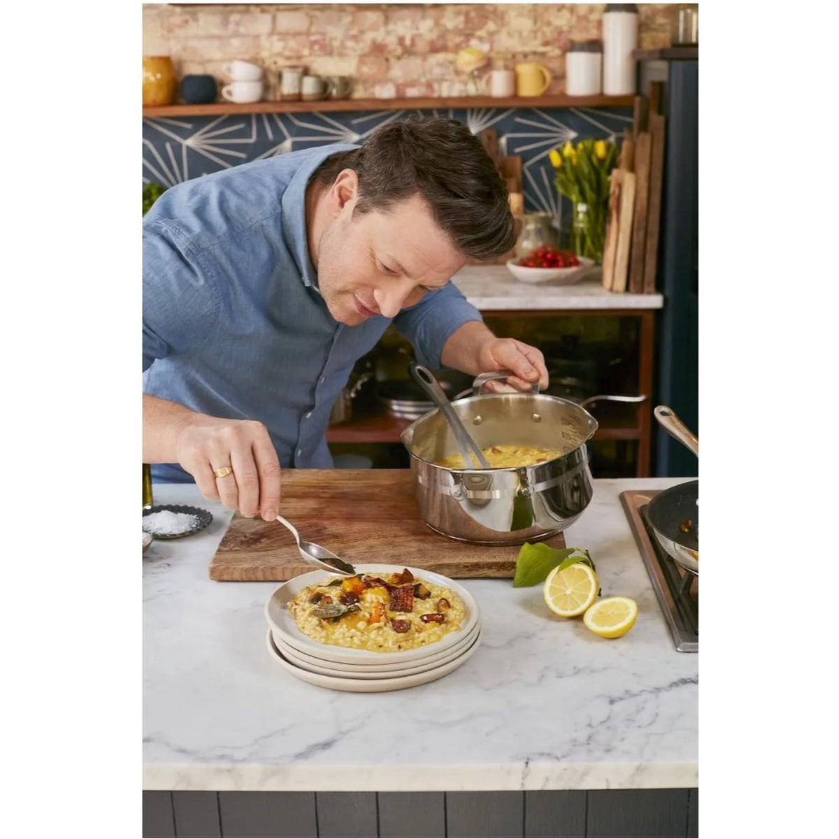 Un chef servant de la nourriture d'une casserole sur des assiettes, avec de la nourriture déjà servie et des citrons à proximité.