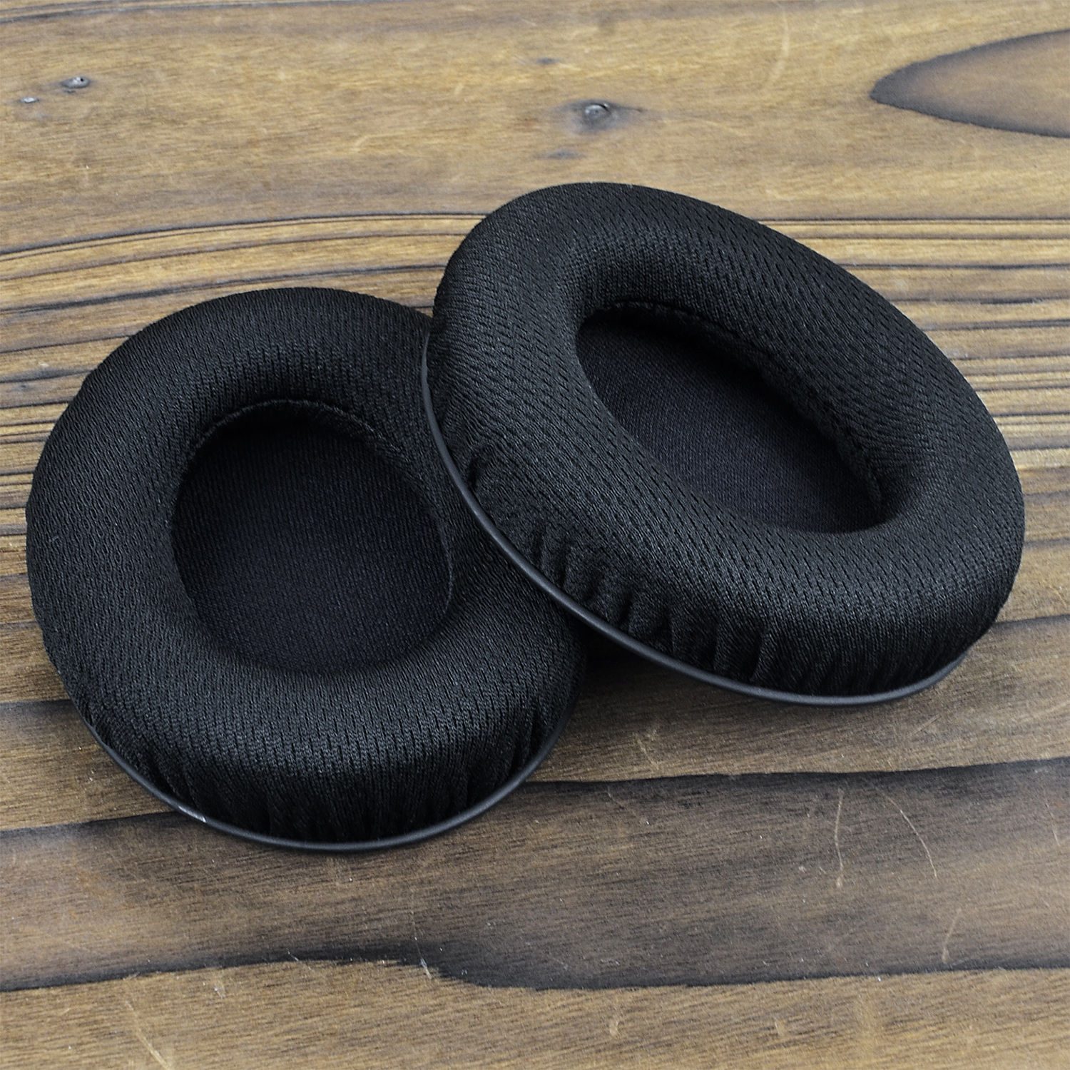 Dwie czarne nauszniki na drewnianej powierzchni.