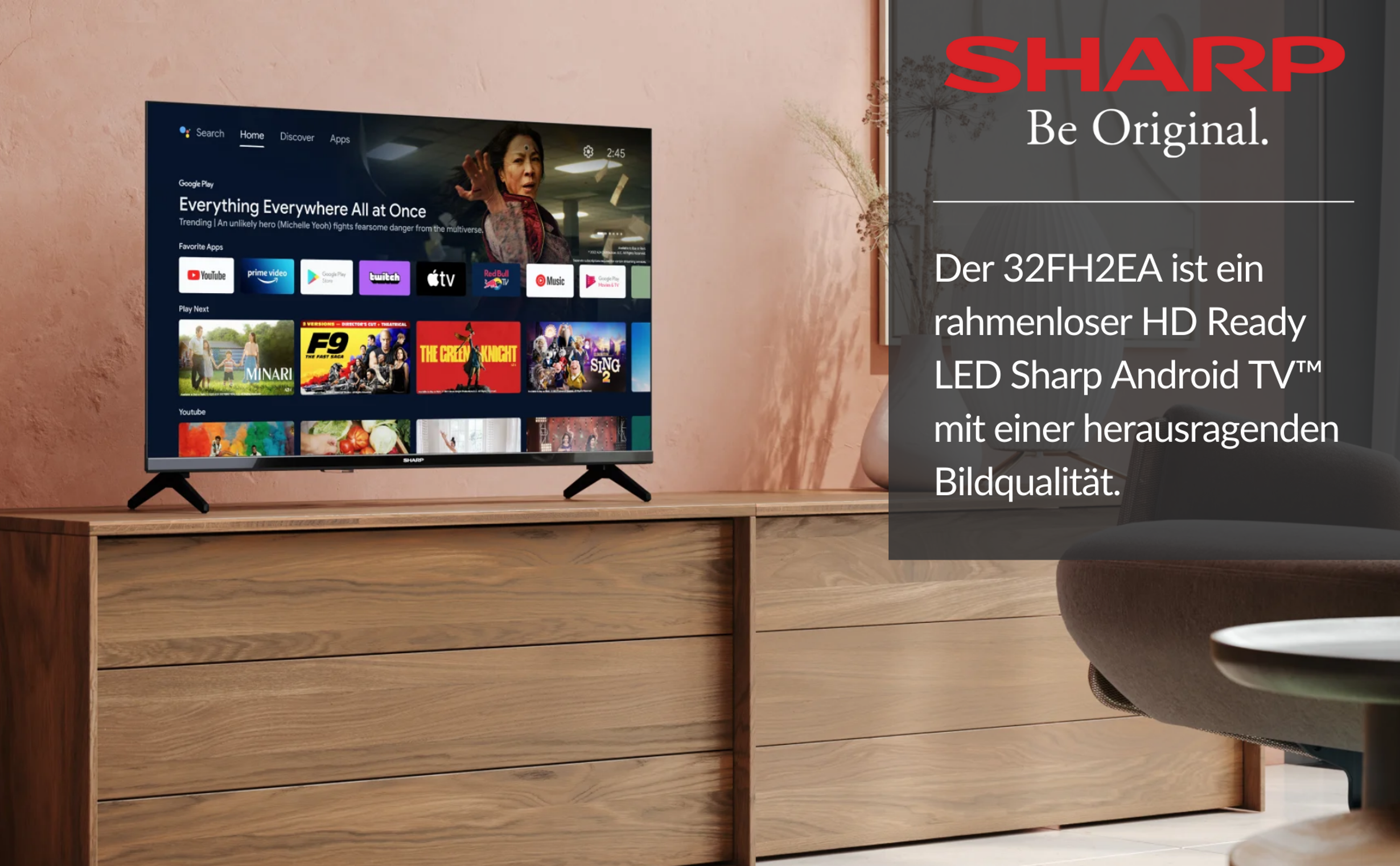 Telewizor Sharp na drewnianej szafce. Tekst na ekranie i po prawej: Sharp, Be Original.