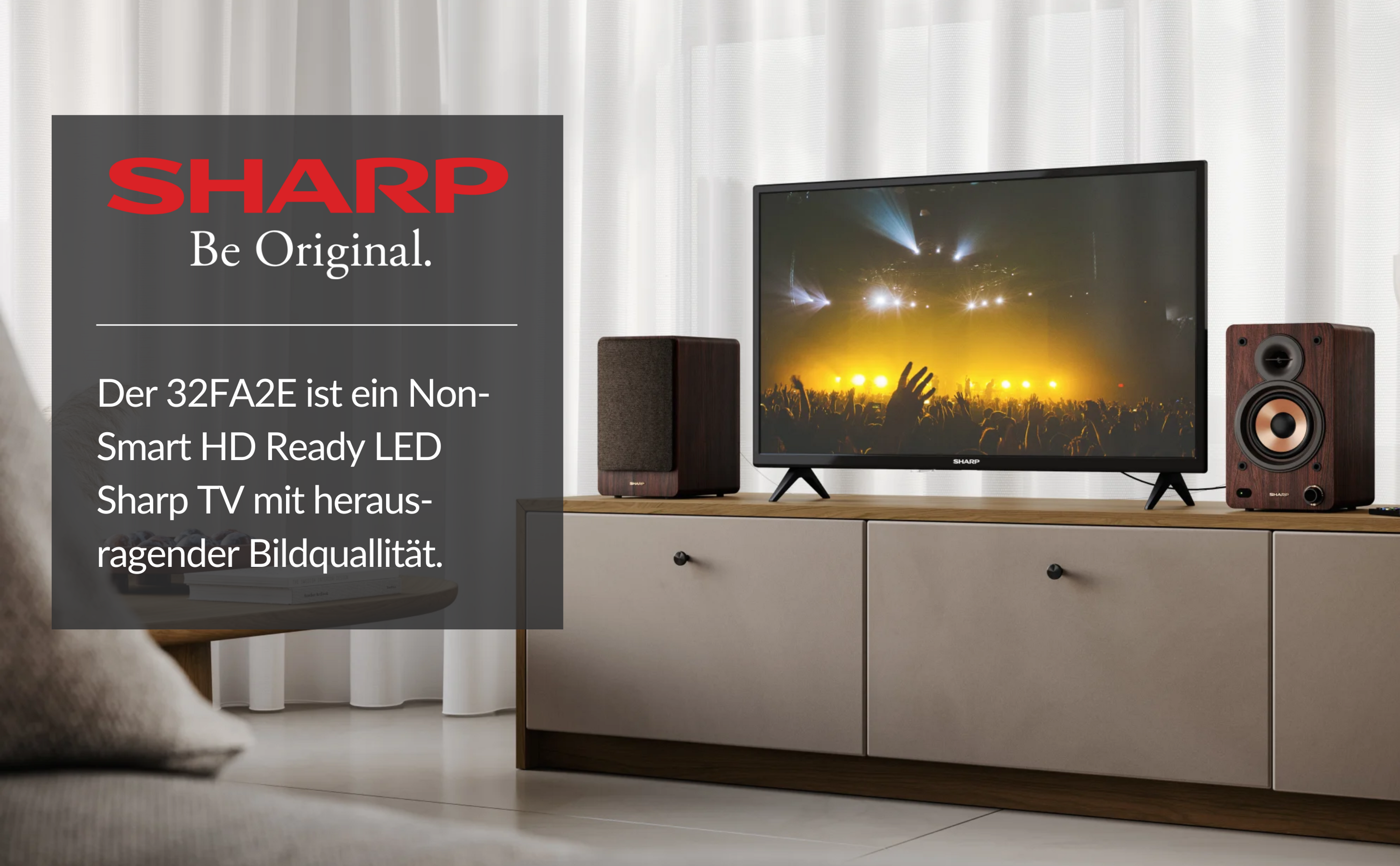 Una TV su un mobile con altoparlanti. Il testo dice "SHARP Be Original" e una descrizione in tedesco.