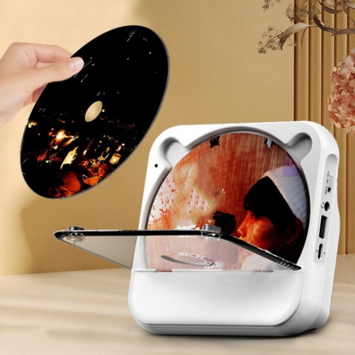 Weißer CD-Player mit offenem Deckel. Eine Hand hält eine CD. Eine CD befindet sich im Player. Lichter reflektieren die CD.