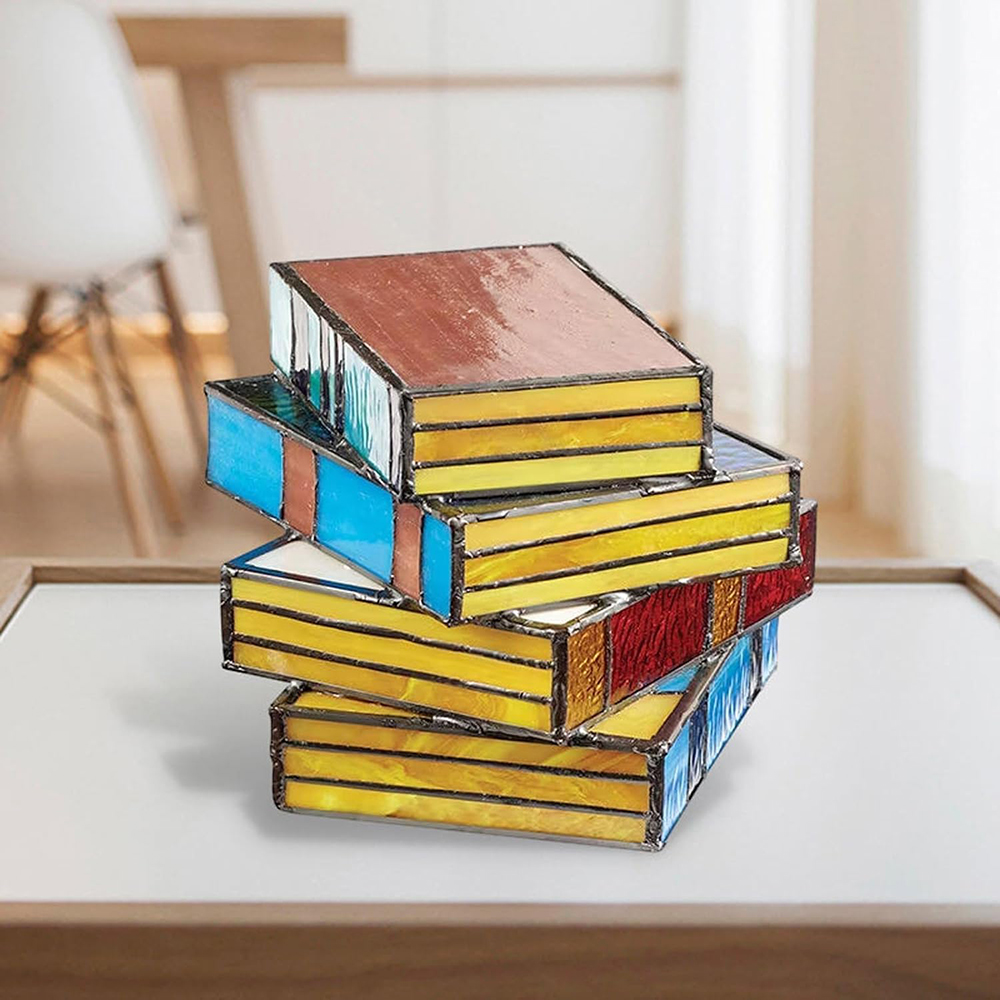Gestapelte bunte Glasmalerei-Boxen auf einem Tisch, mit weißem Hintergrund.