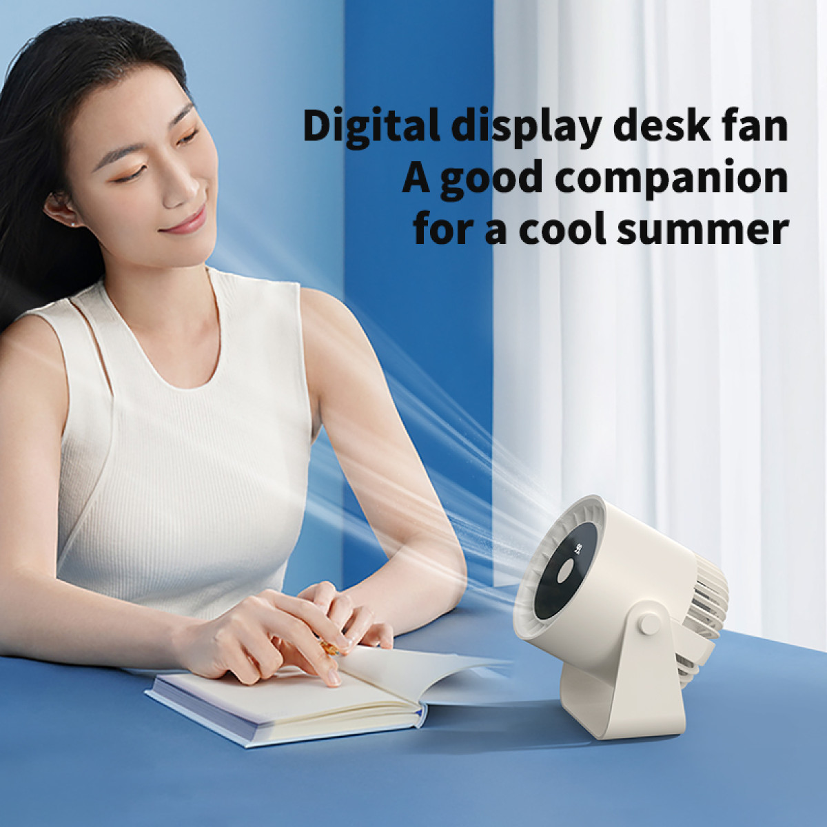 Woman at a table with a desk fan. Fan is white, table is blue. Text: Digital display desk fan.