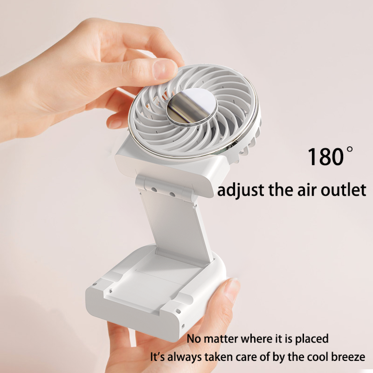 A white portable fan, adjustable, being held by hands on a white surface with text.