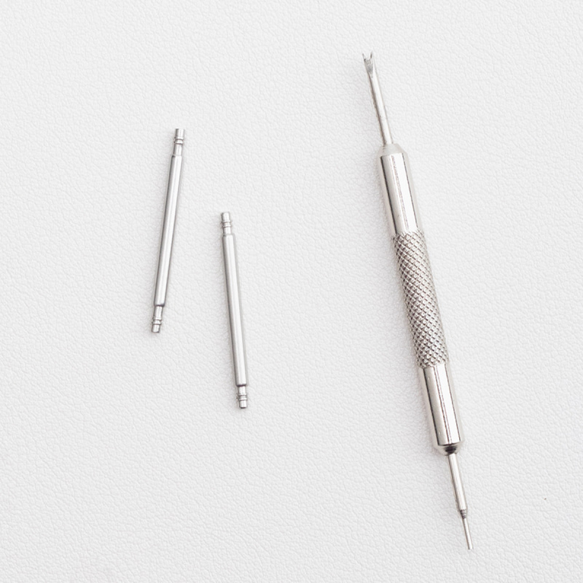 Narzędzia do naprawy zegarków: trzy szpilki i narzędzie z teksturowanym uchwytem.